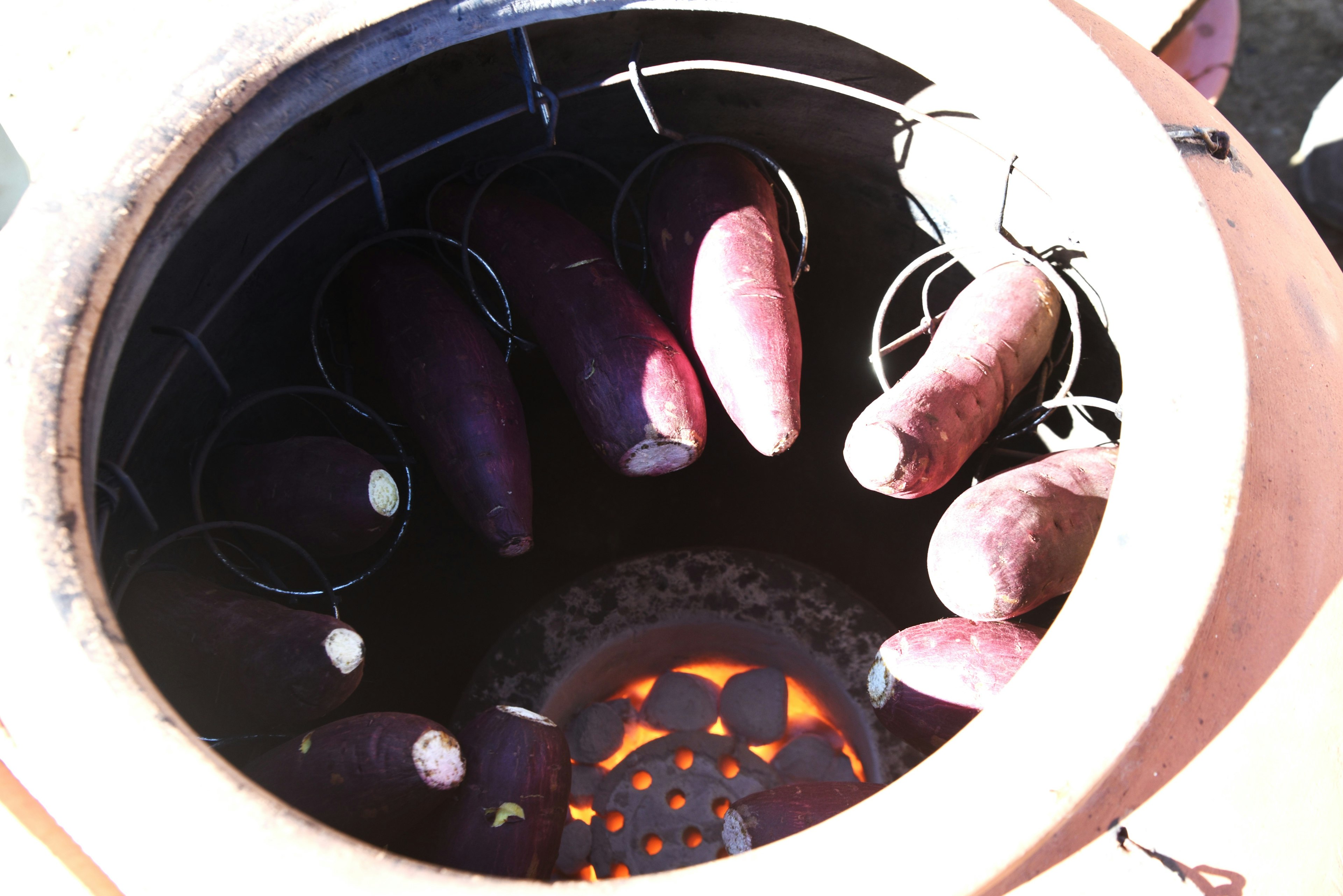 Patates douces dans un pot en terre cuite pour rôtir avec des flammes visibles