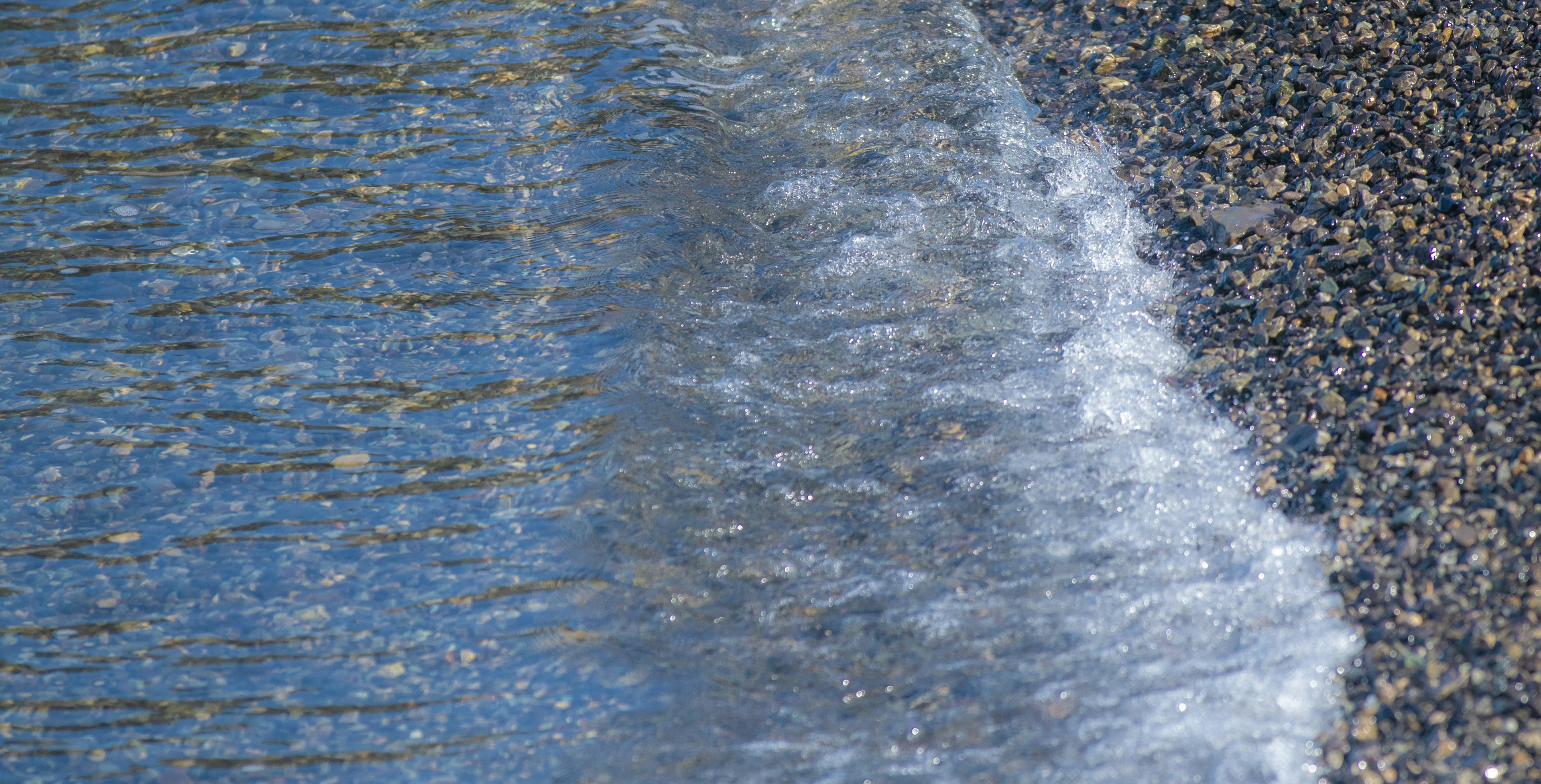 A natural scene showing the boundary between water and gravel