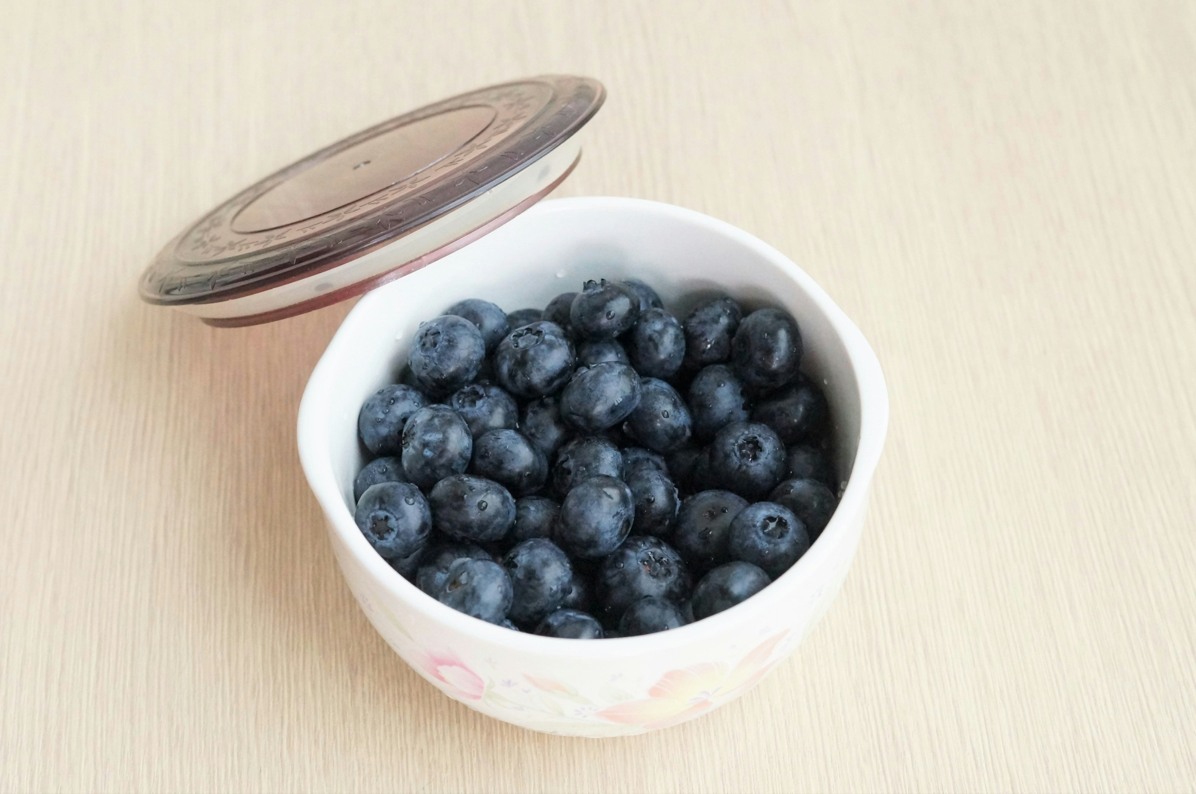 Eine Schüssel mit frischen Heidelbeeren und einem Holzdeckel