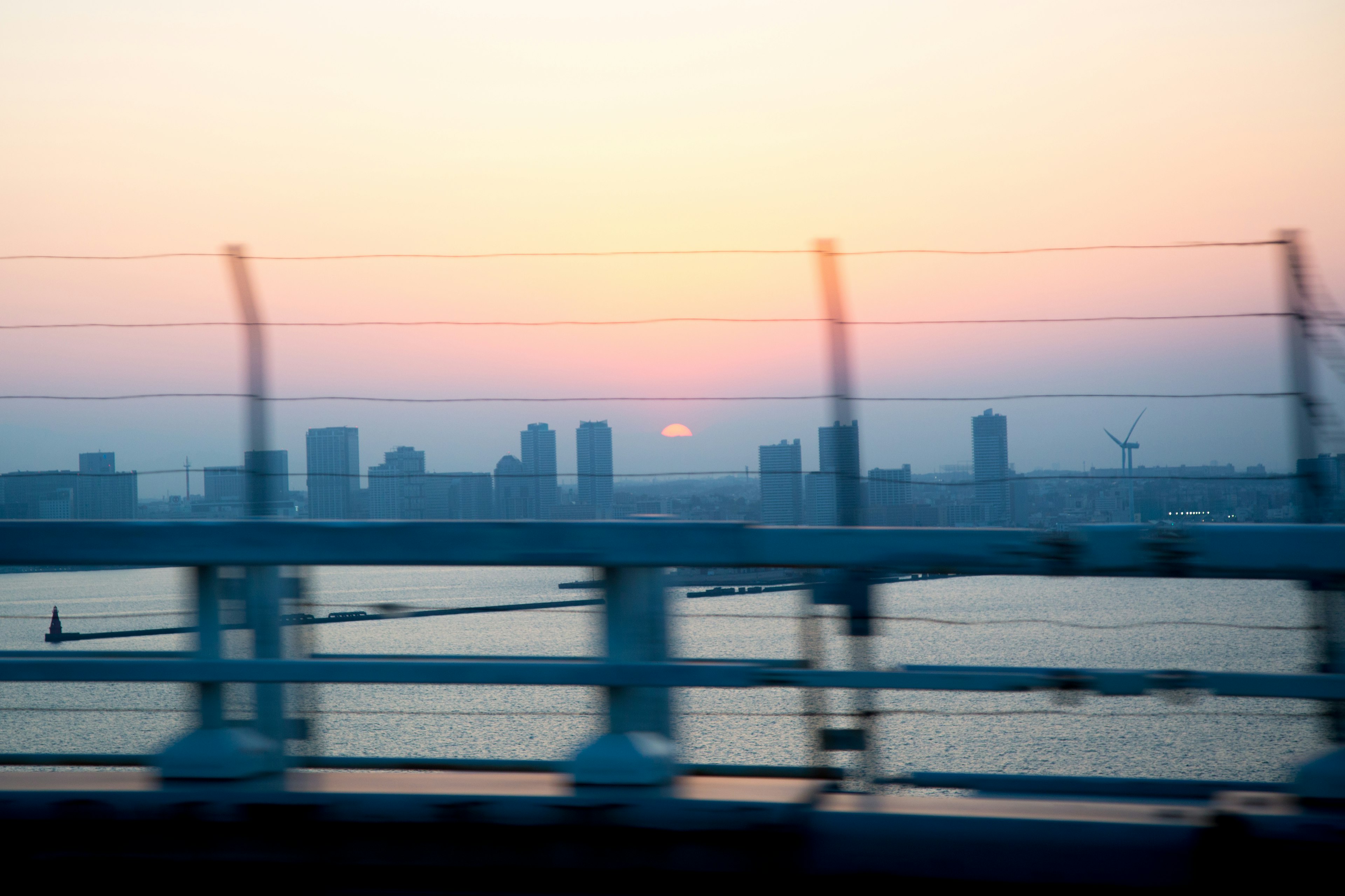 夕日が沈む都市のシルエットとフェンスが写る風景