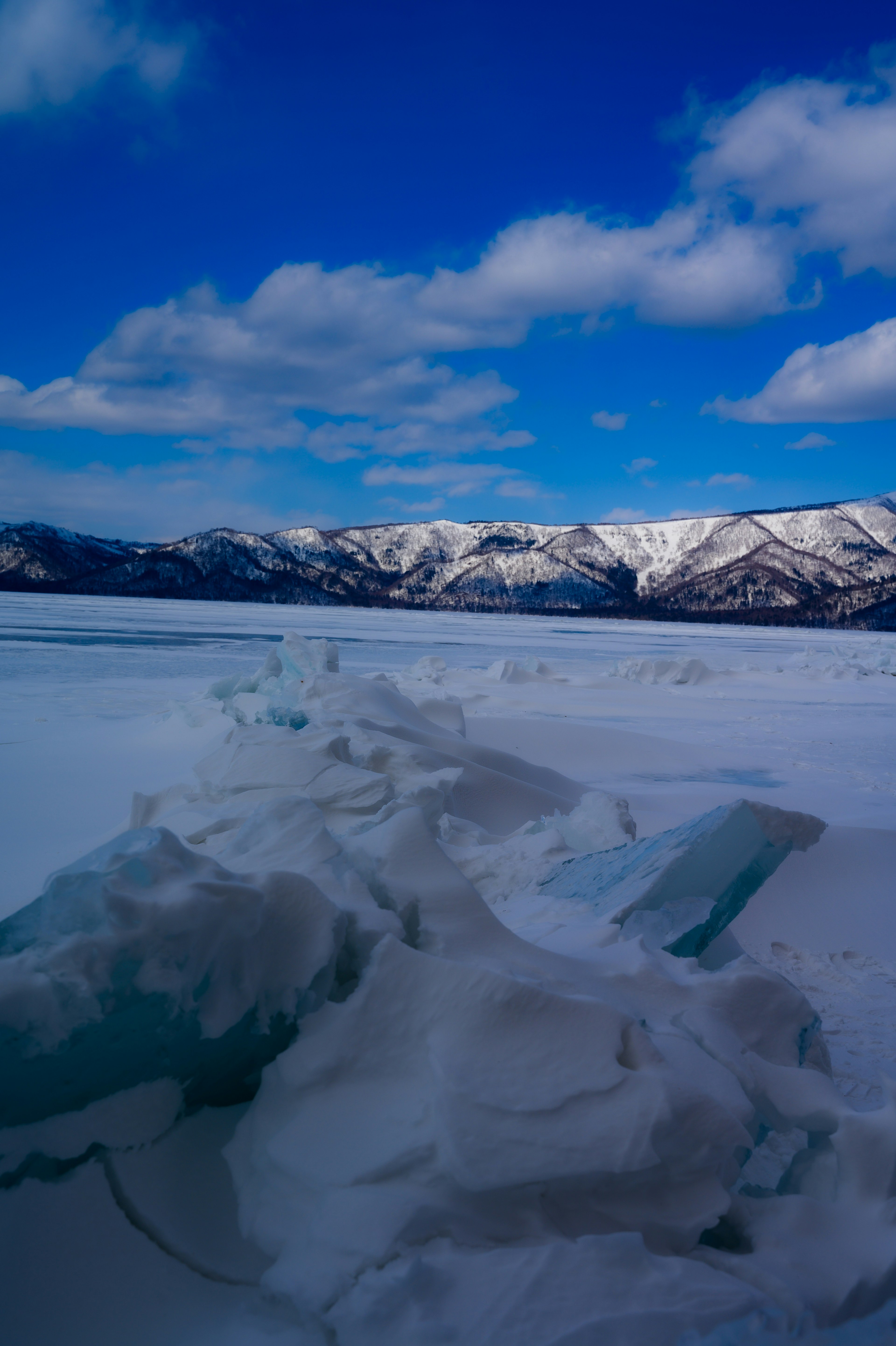 Landschaft mit schneebedeckten Bergen und Eisspalten unter einem blauen Himmel