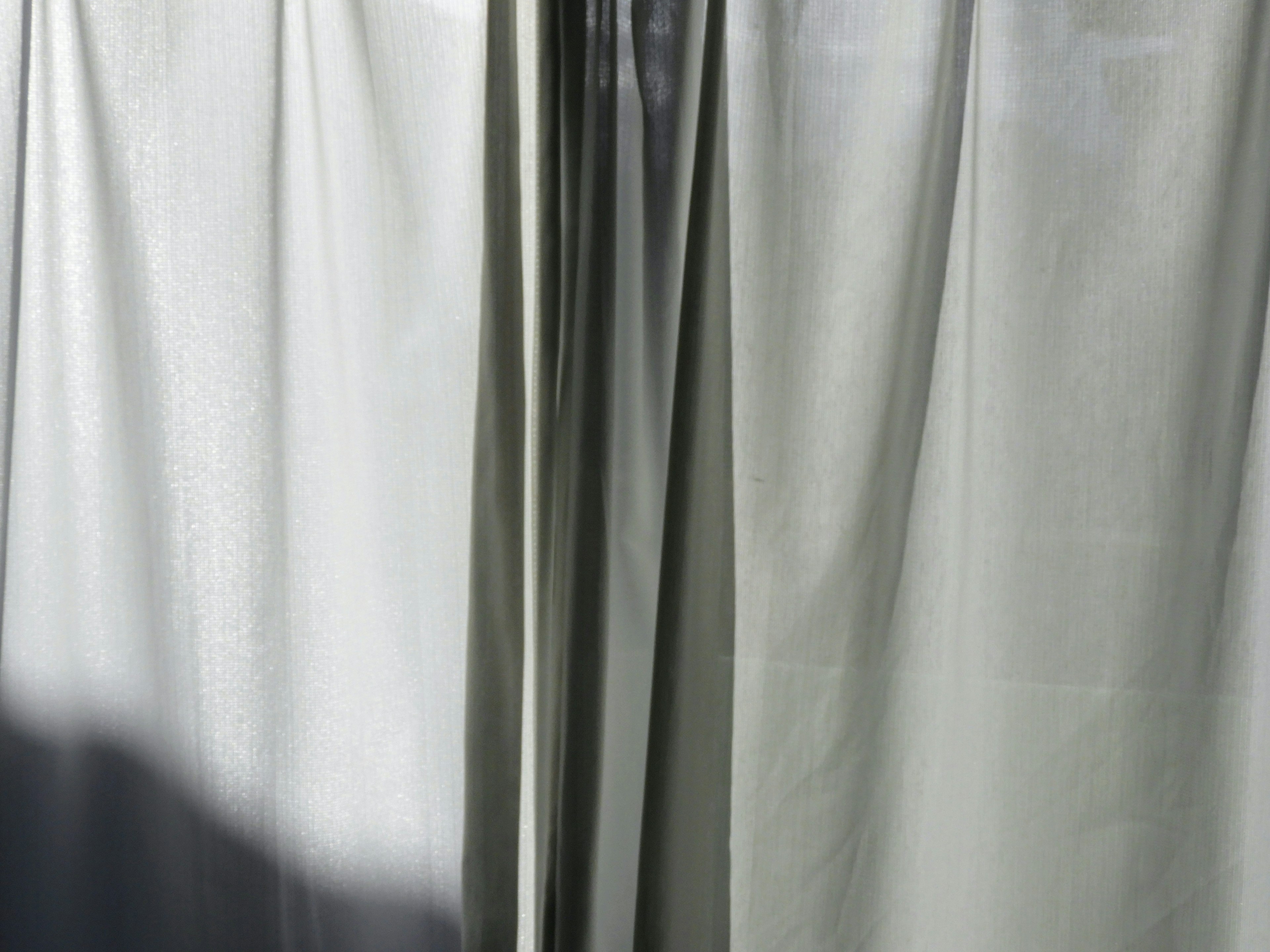 Light gray curtains partially open allowing sunlight to filter through