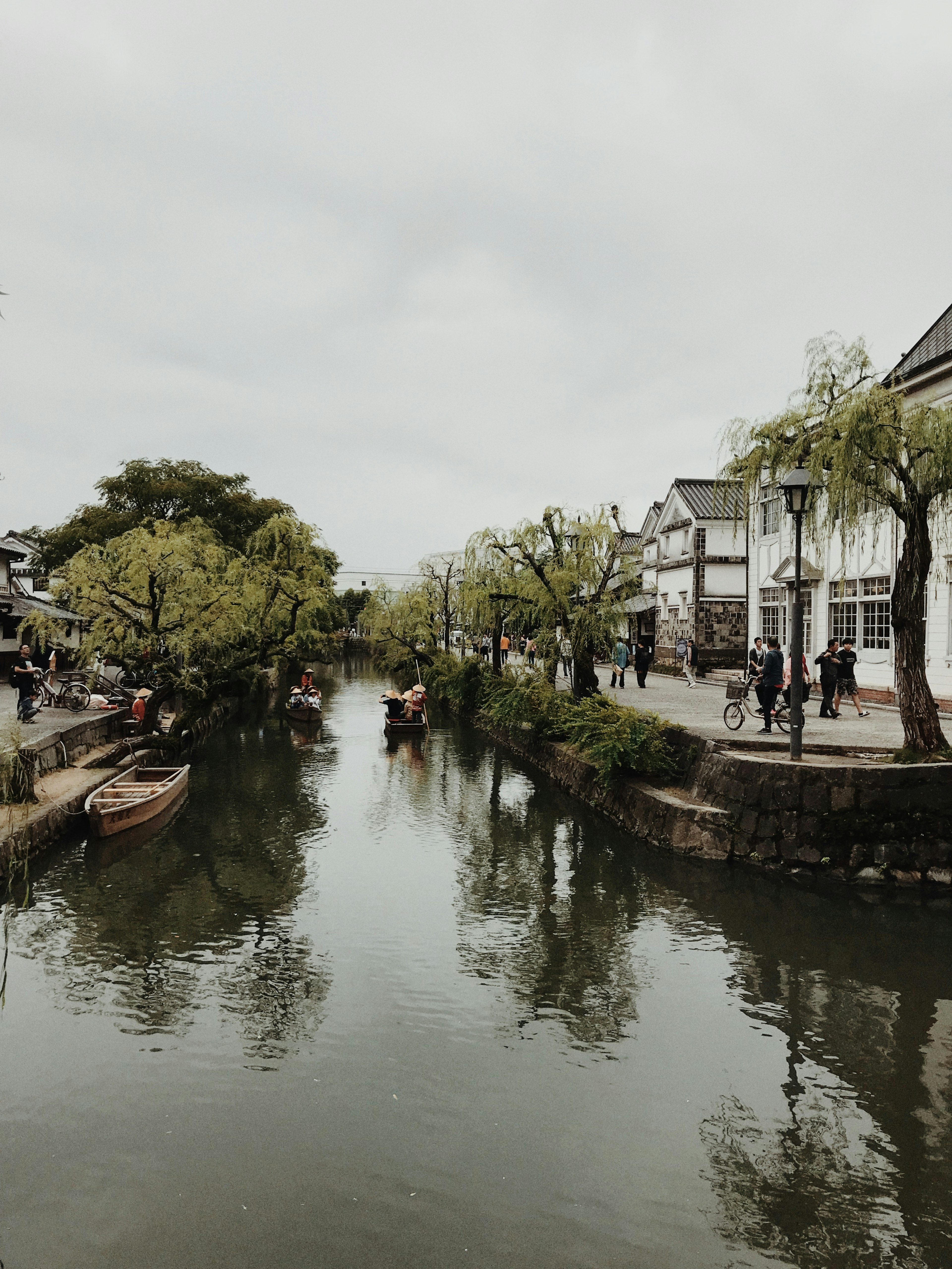 Scenic view of a calm river lined with green trees and traditional buildings