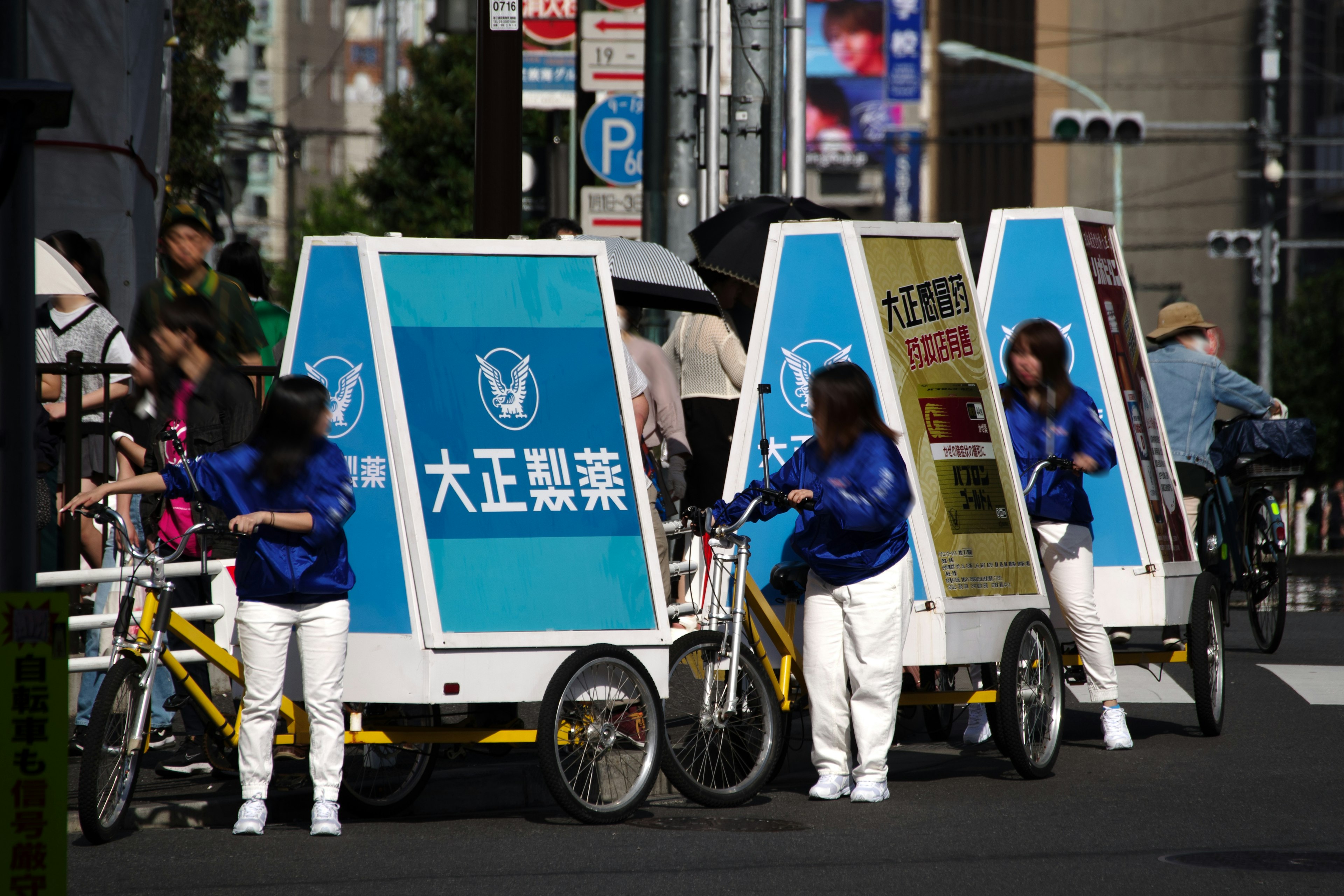 Staff in blue jackets operating bicycle advertisements at a street corner in Tokyo