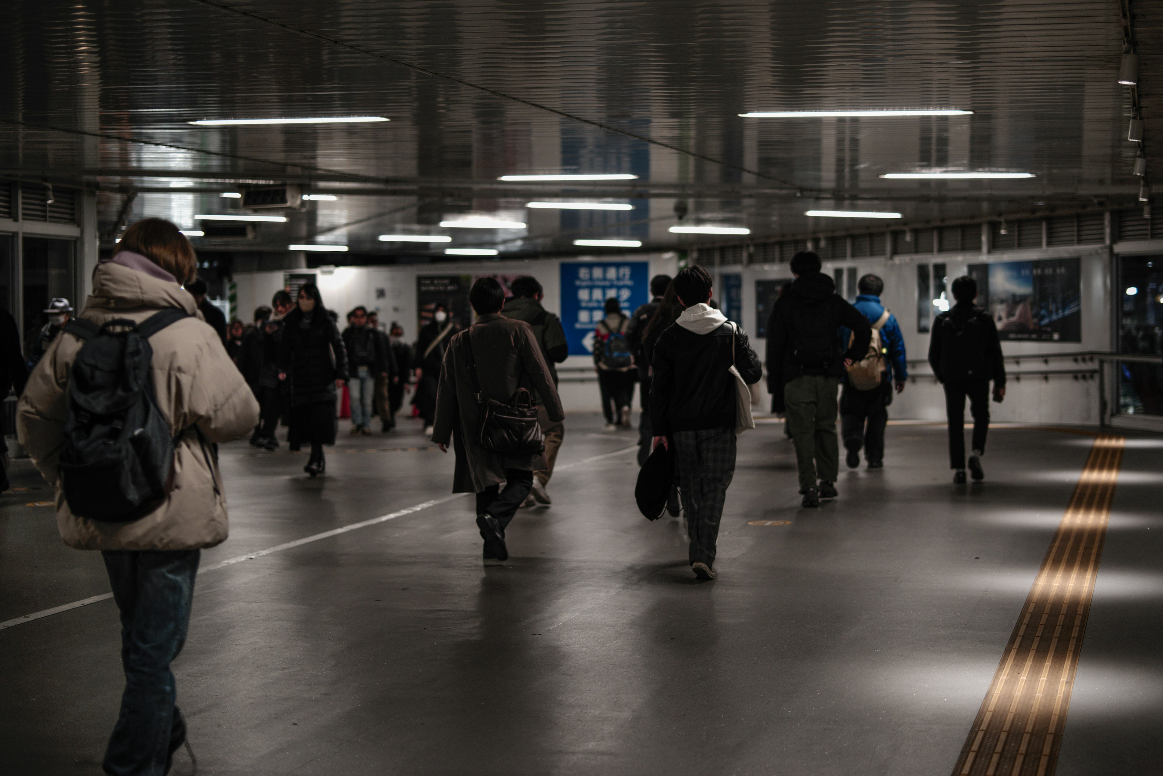 People walking in a modern underground passage with overhead lighting