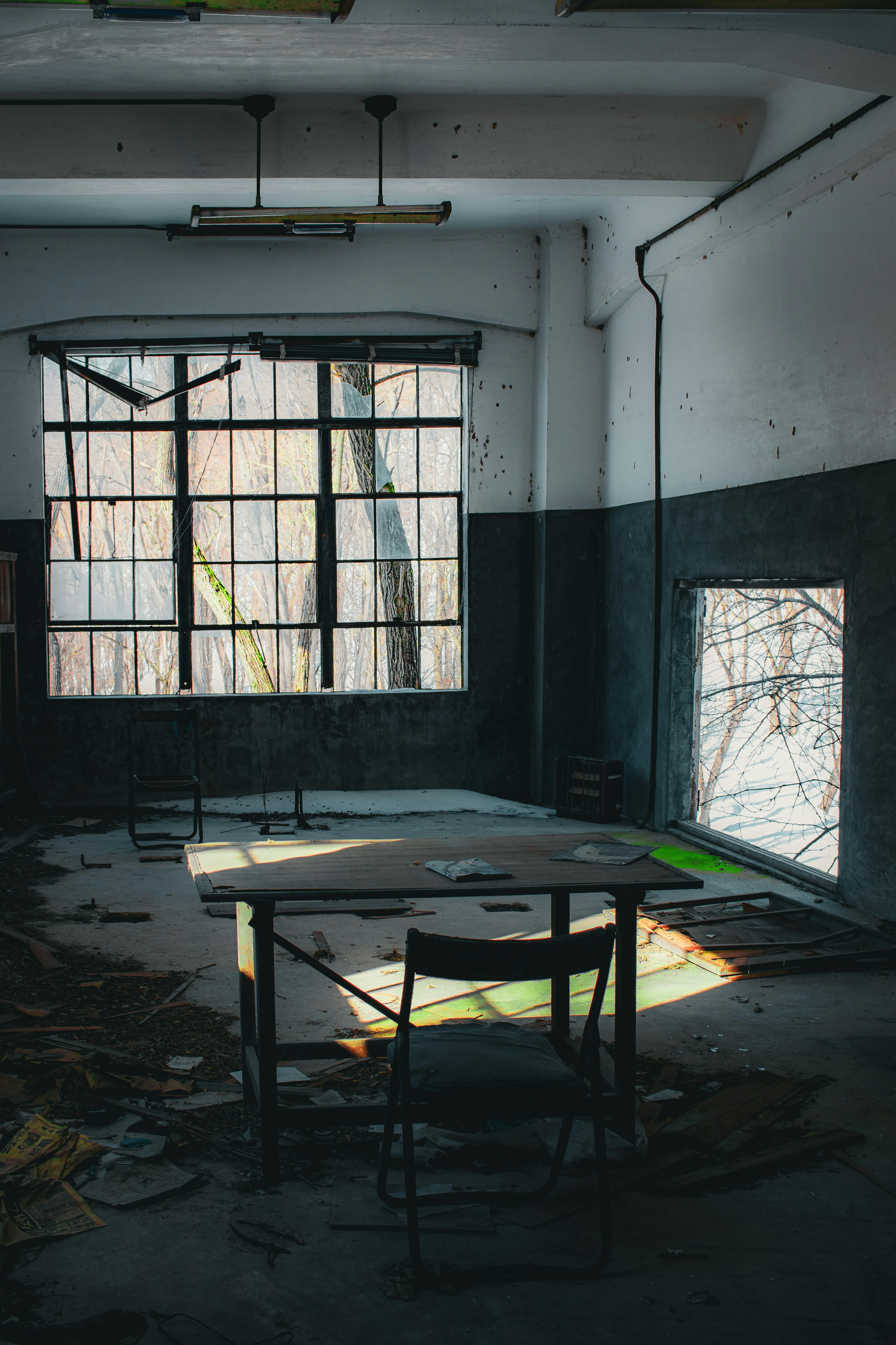 Empty room with a table and chair sunlight streaming through broken windows