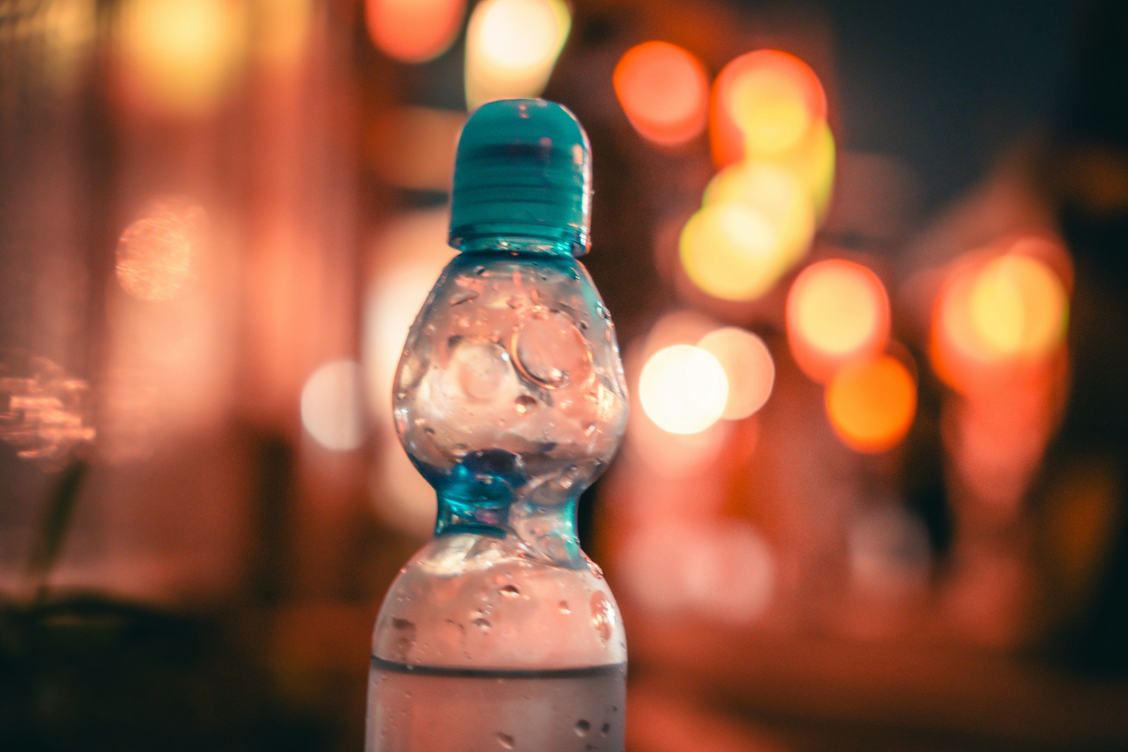 Primer plano de una botella de agua con un fondo colorido borroso de noche