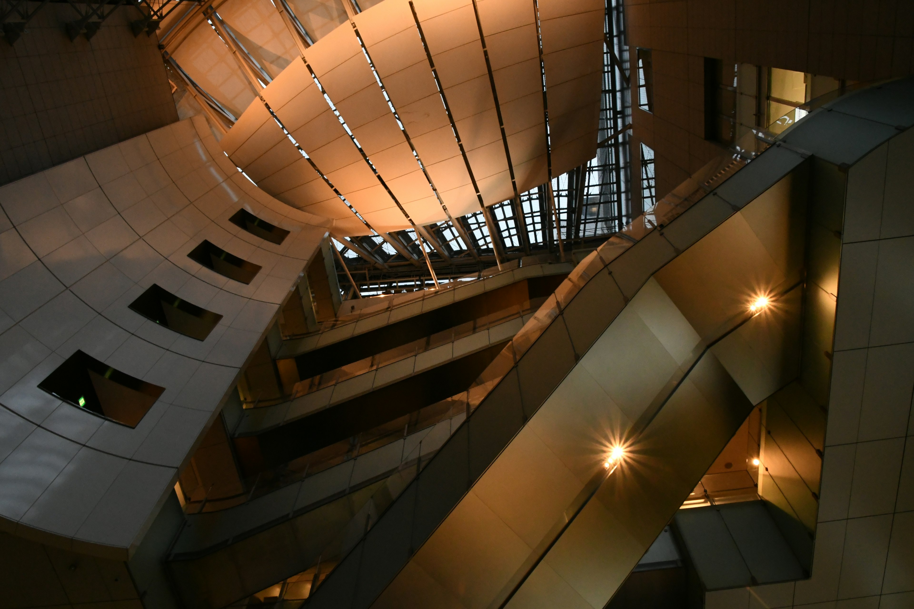 View of a modern building's interior structure from above featuring bright lighting and curved design