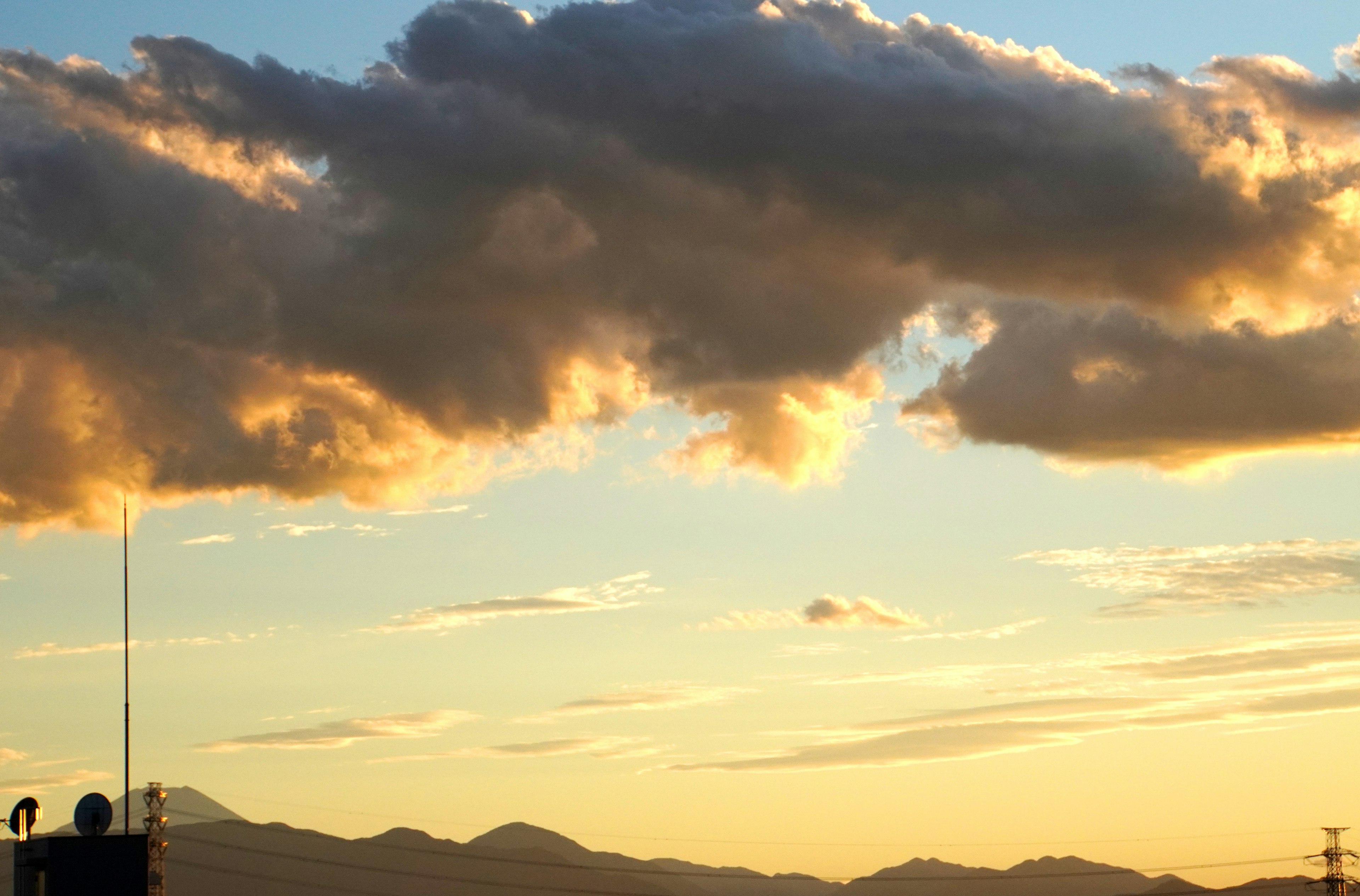 Nubes contra un cielo de atardecer vibrante con siluetas de montañas