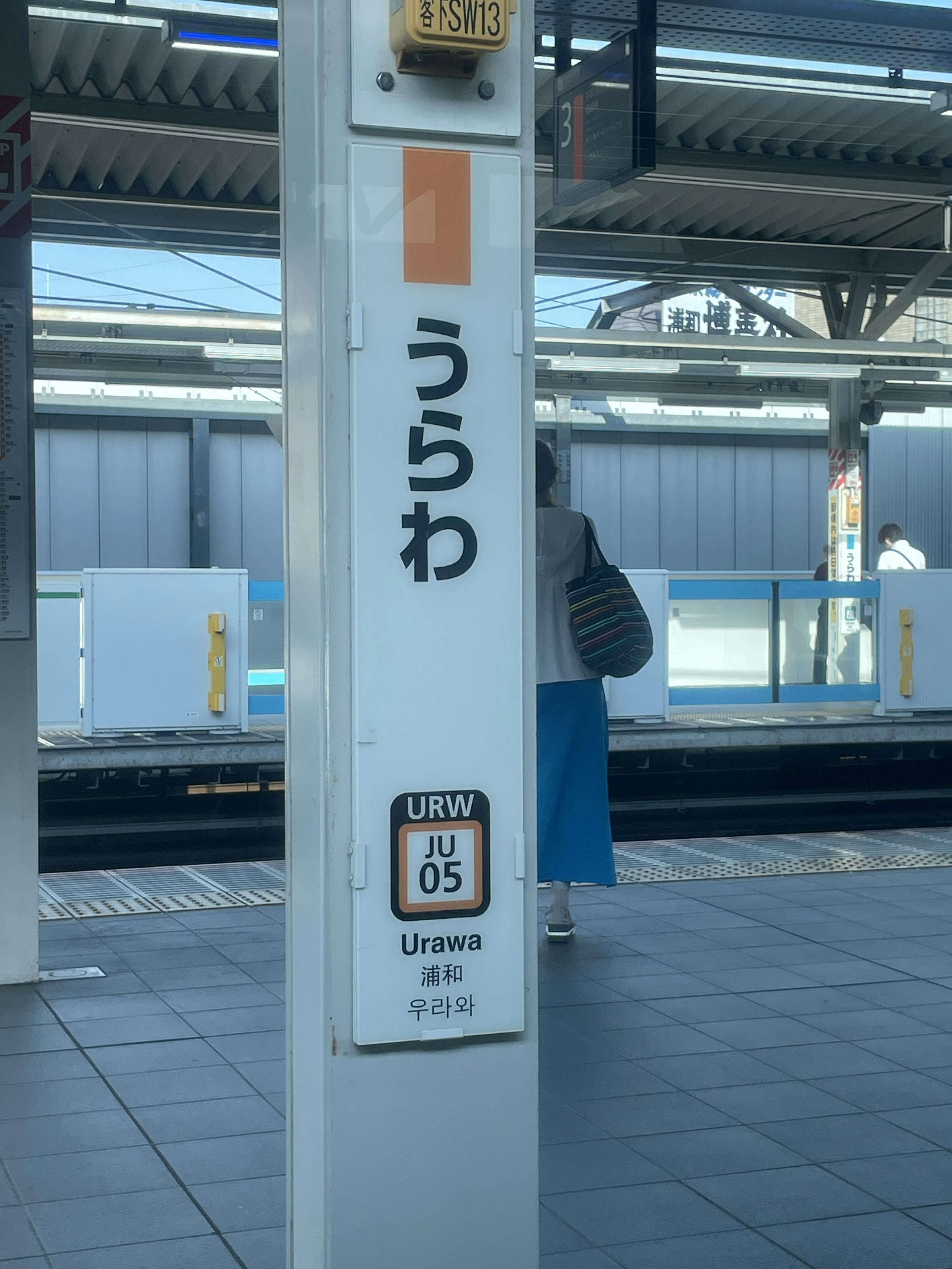 Urawa station sign with a person in the background