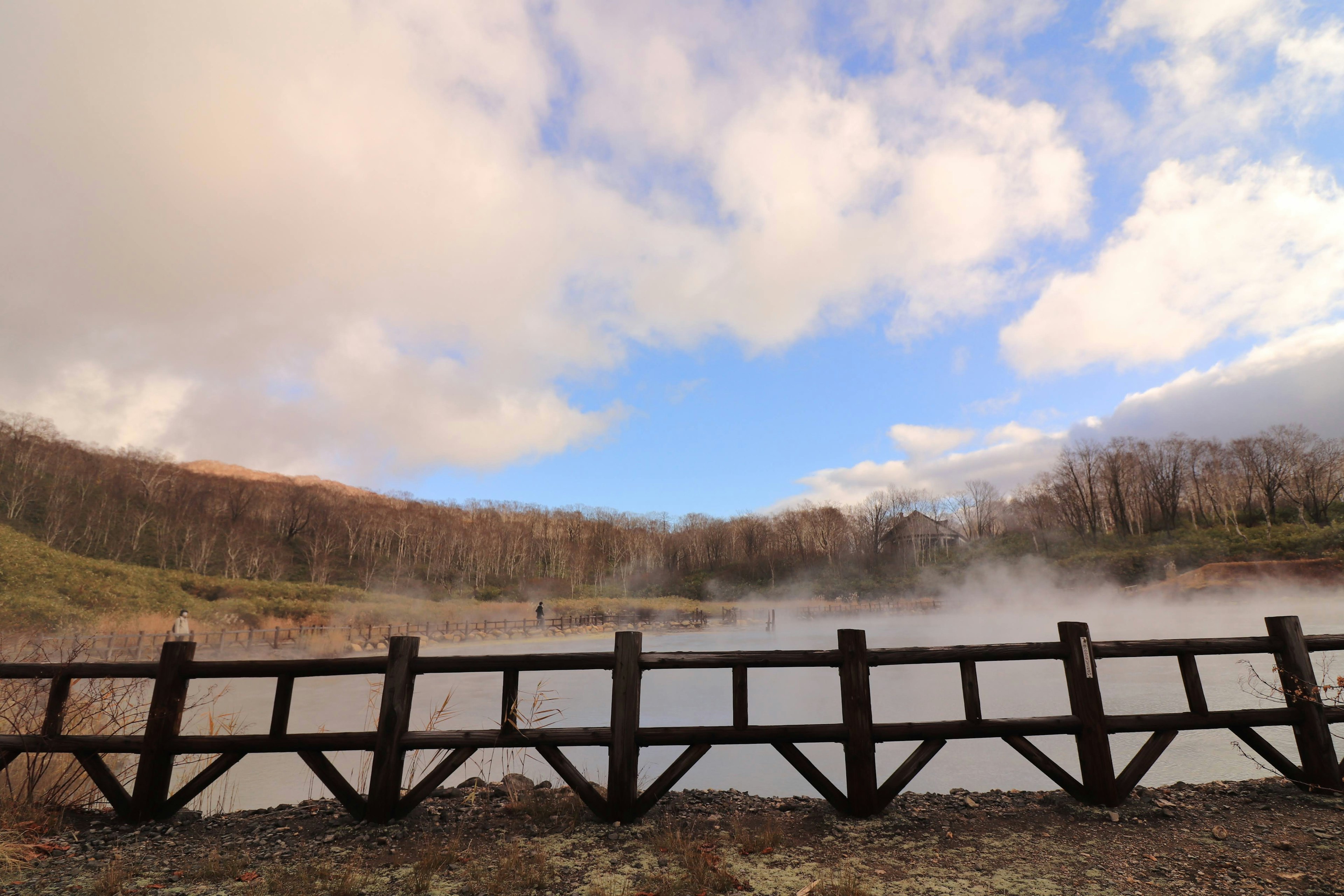 Wooden bridge overlooking a misty lake surrounded by hills