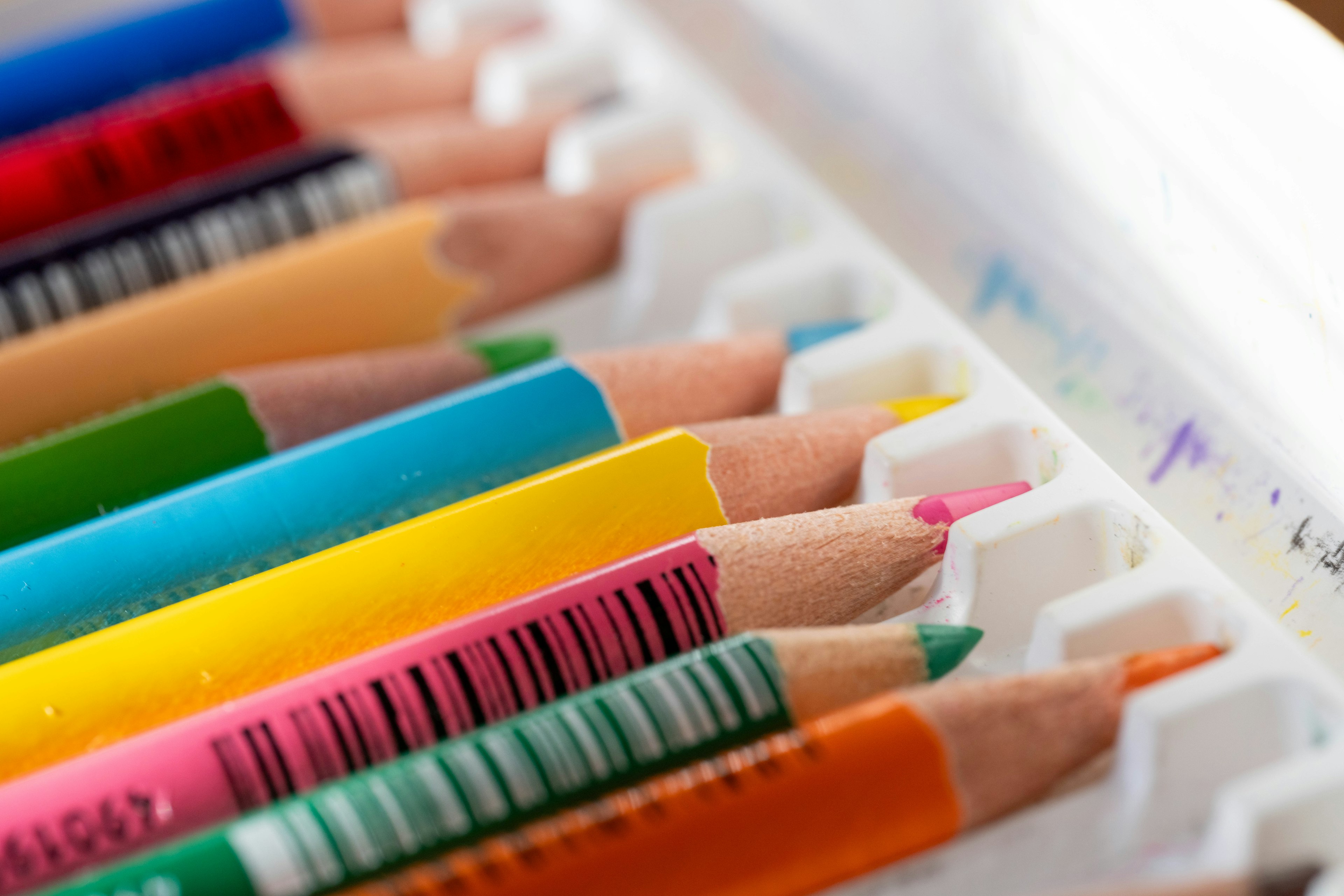 Colorful colored pencils neatly arranged in a white case with tips visible