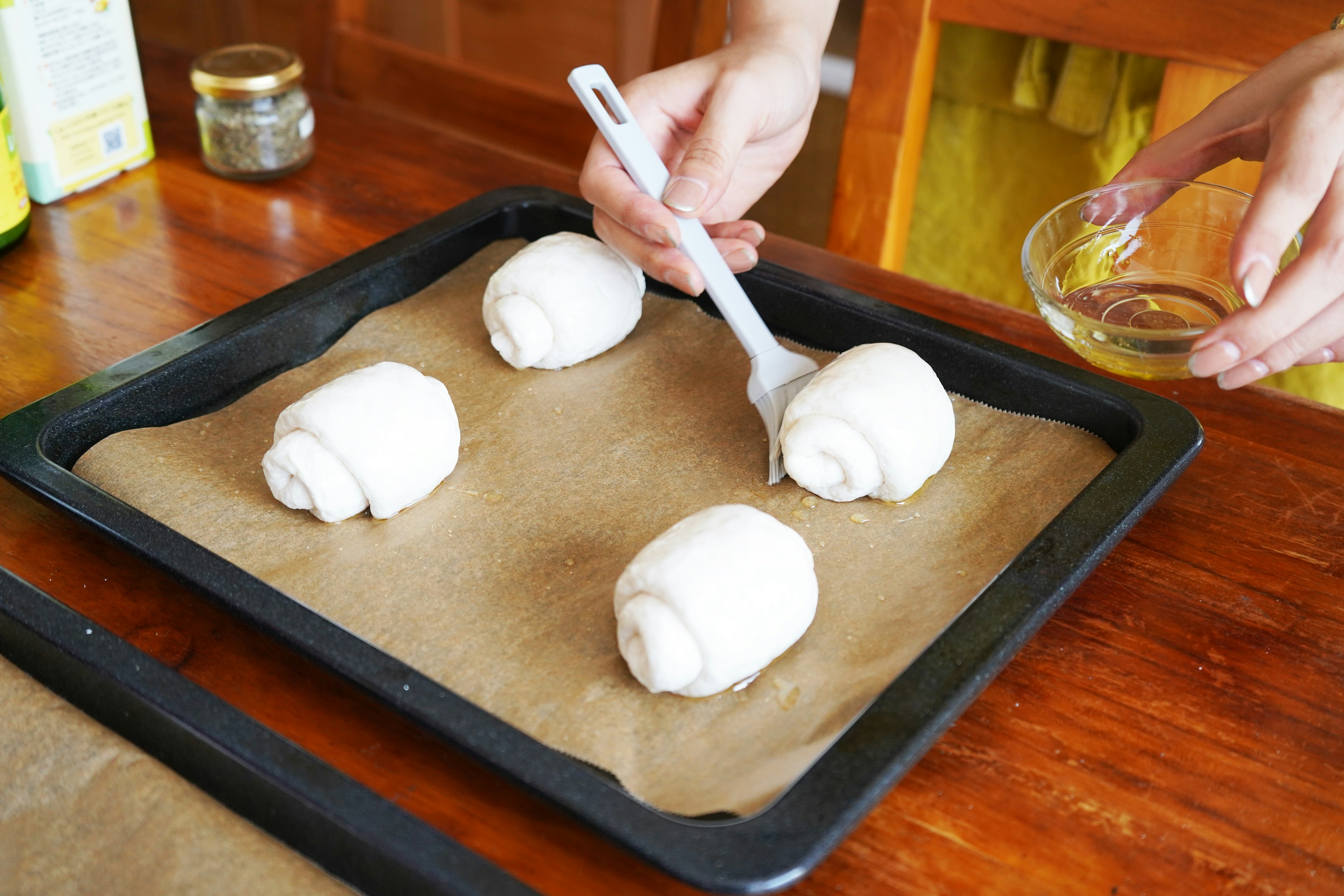 Applying egg wash to raw dough on a baking tray