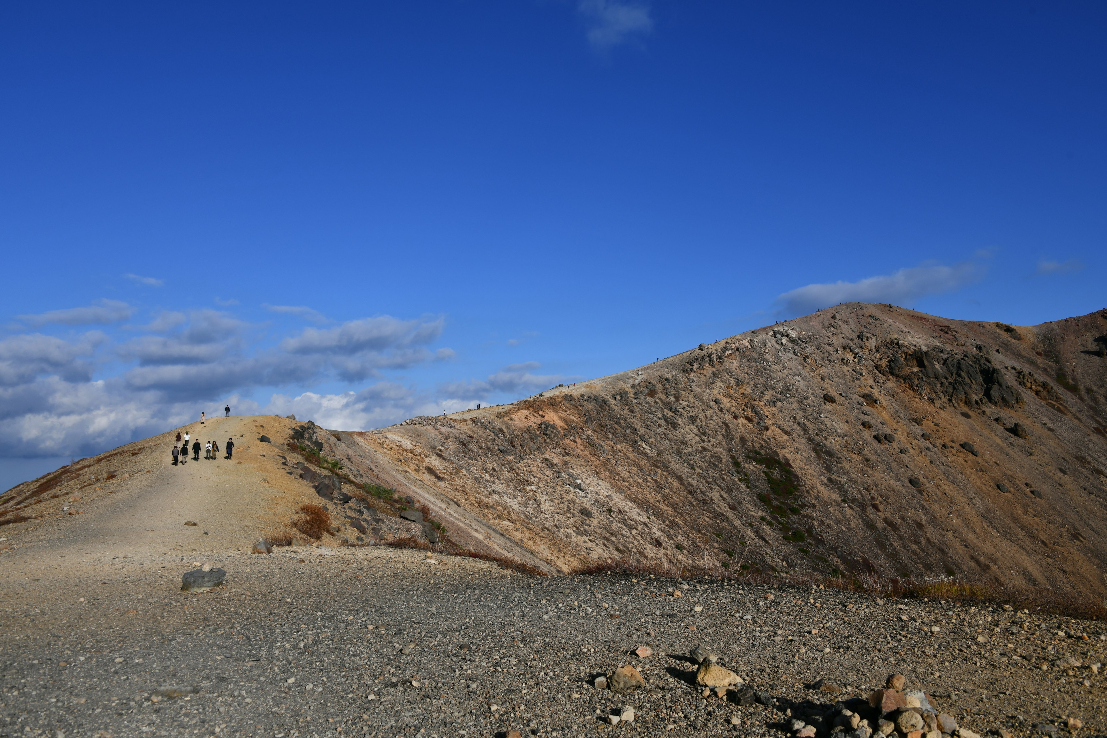 Paisaje montañoso bajo un cielo azul con excursionistas