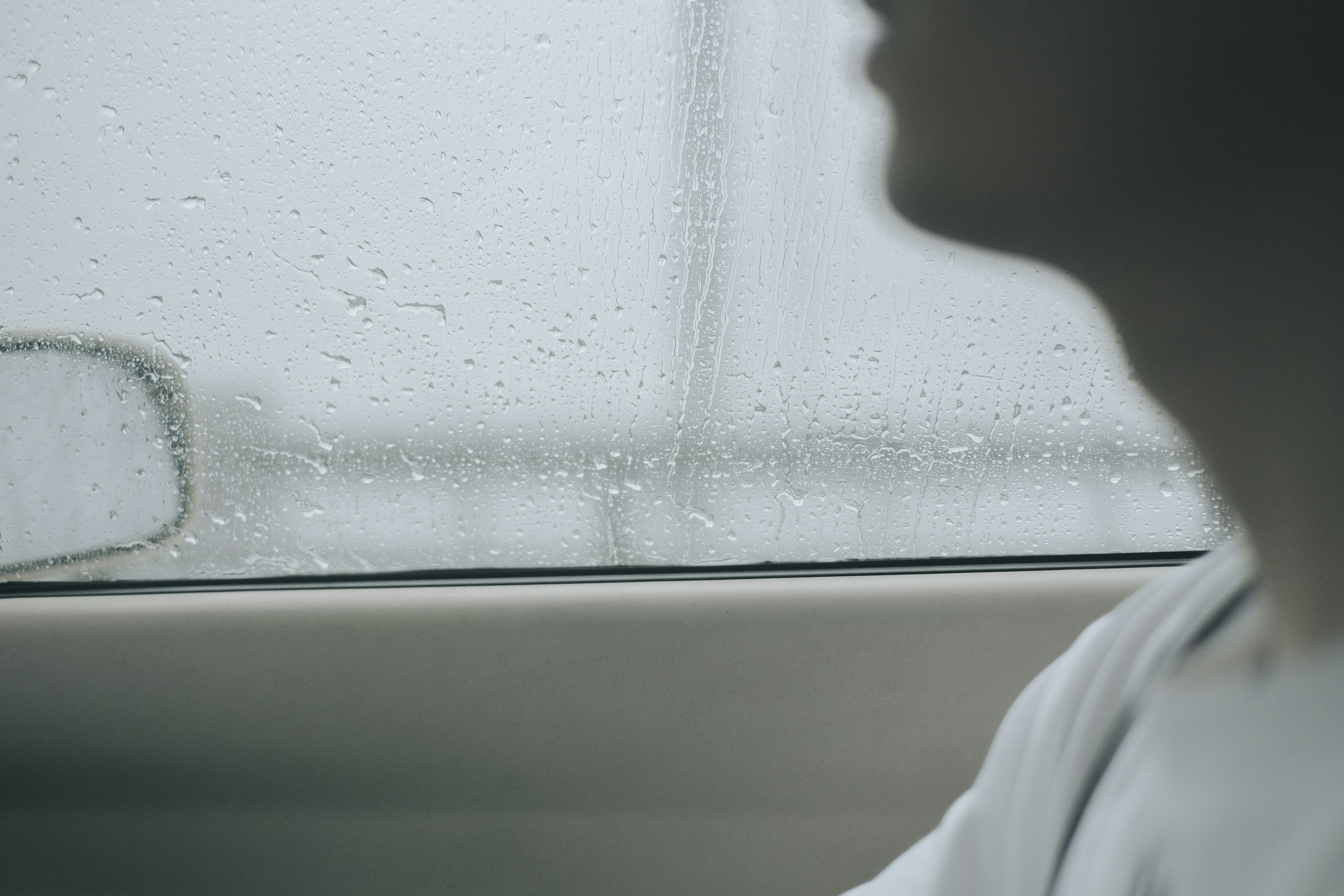 Profile of a person seen through a rain-covered window