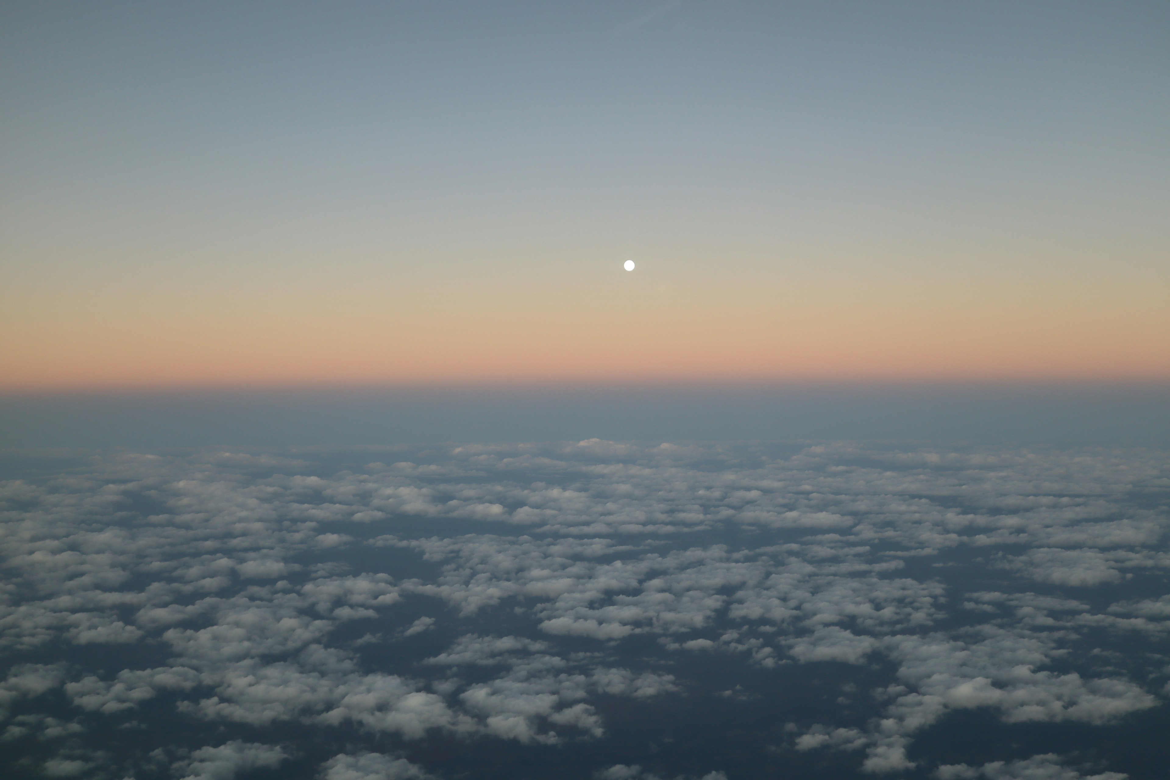 空の青とオレンジのグラデーションと雲の上に浮かぶ月