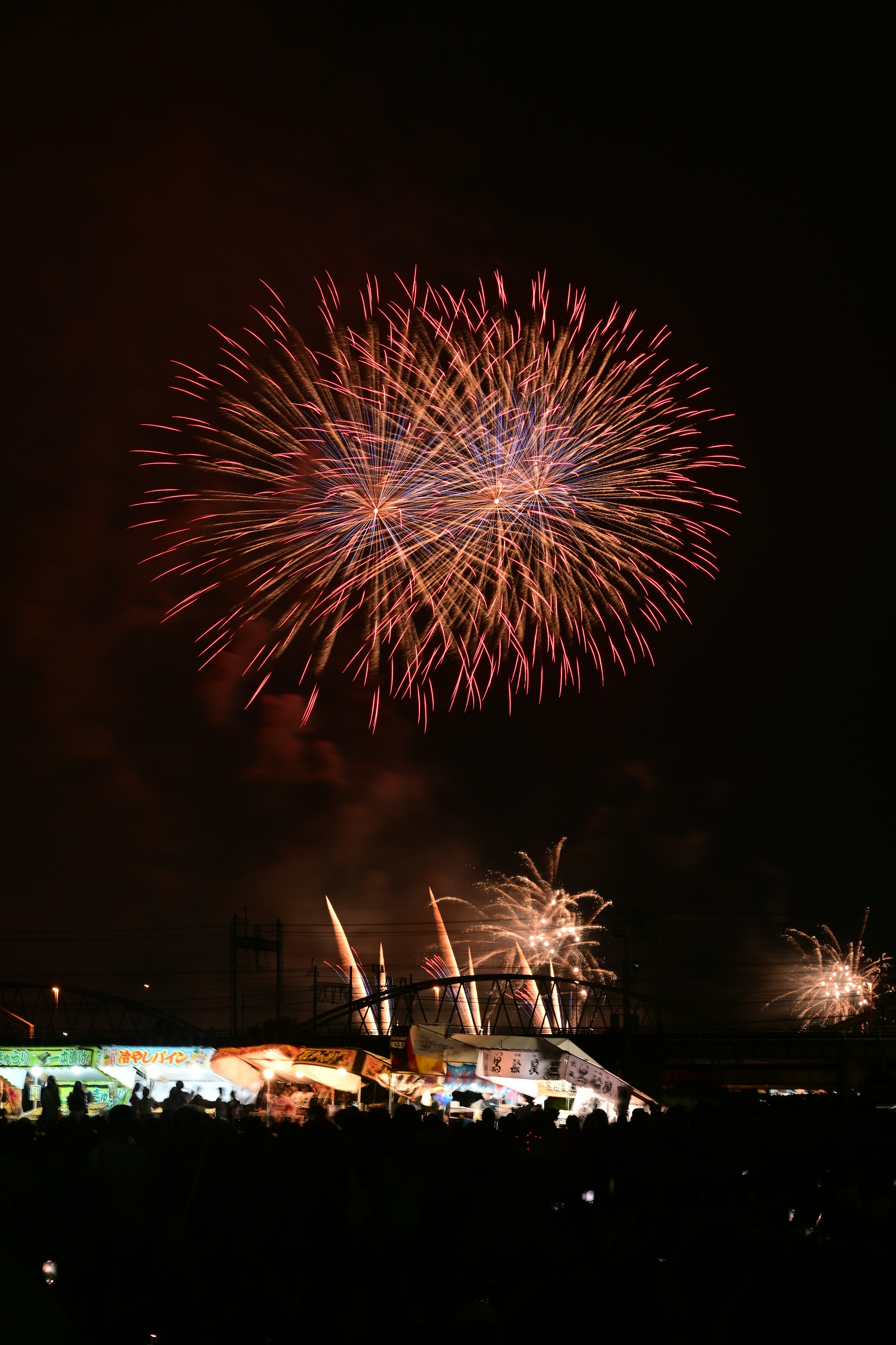 Bunte Feuerwerk-Show erhellt den Nachthimmel mit Silhouetten von Zuschauern