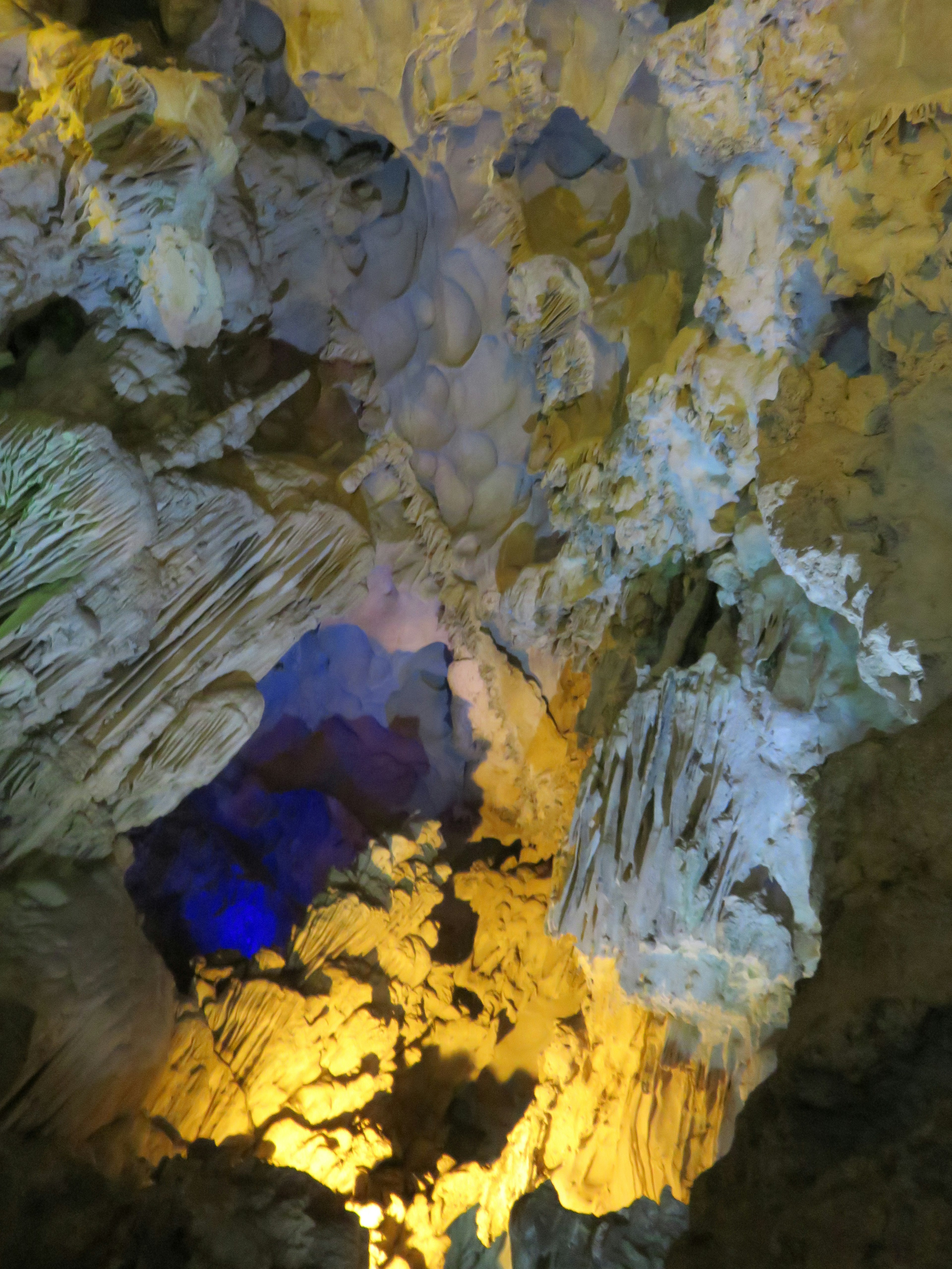 Interno di una grotta con formazioni rocciose colorate illuminate da luci blu e gialle