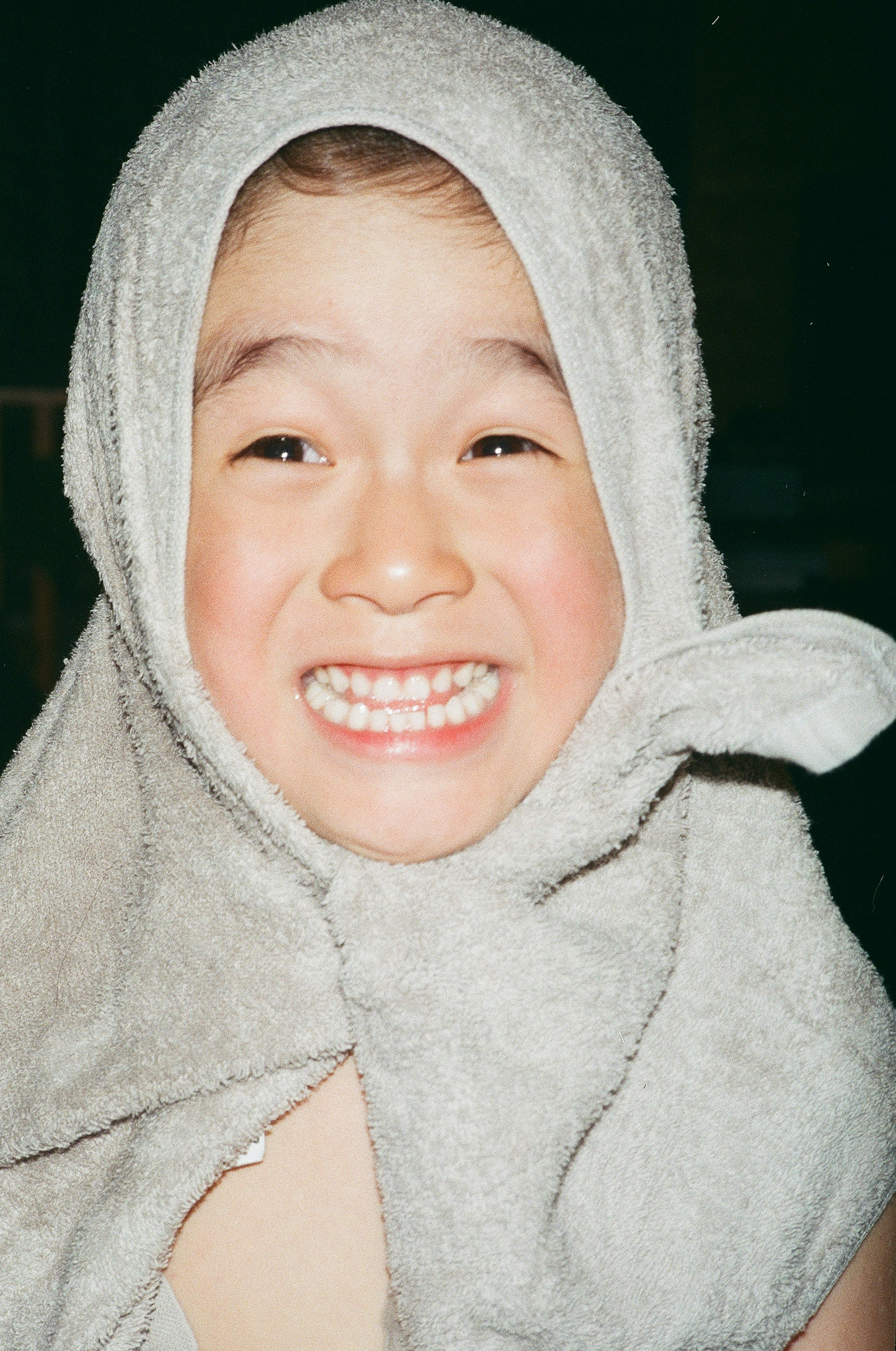 Child with a towel on their head smiling widely