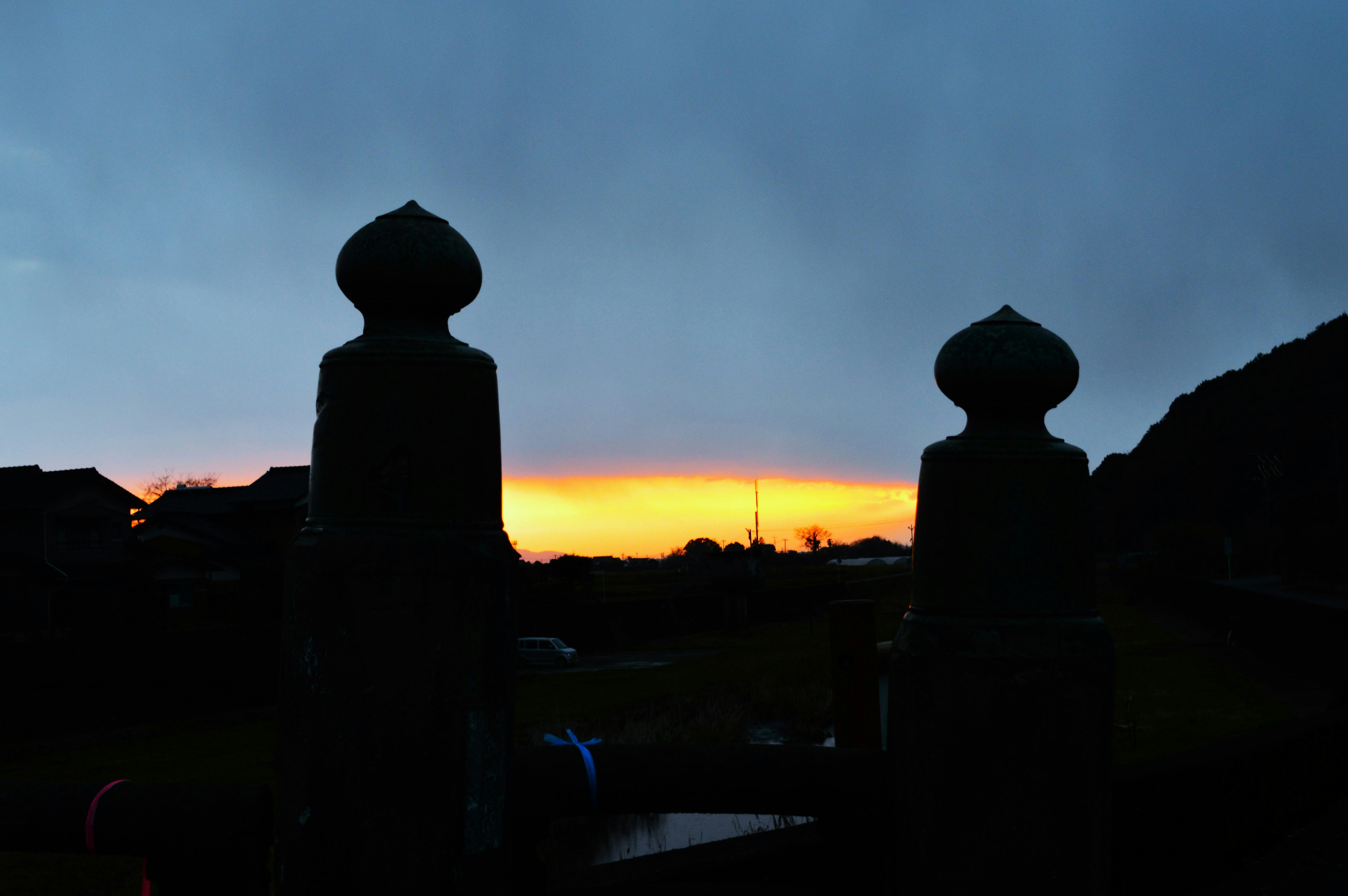 Zwei Statuen im Silhouettenformat vor einem lebhaften Sonnenuntergang