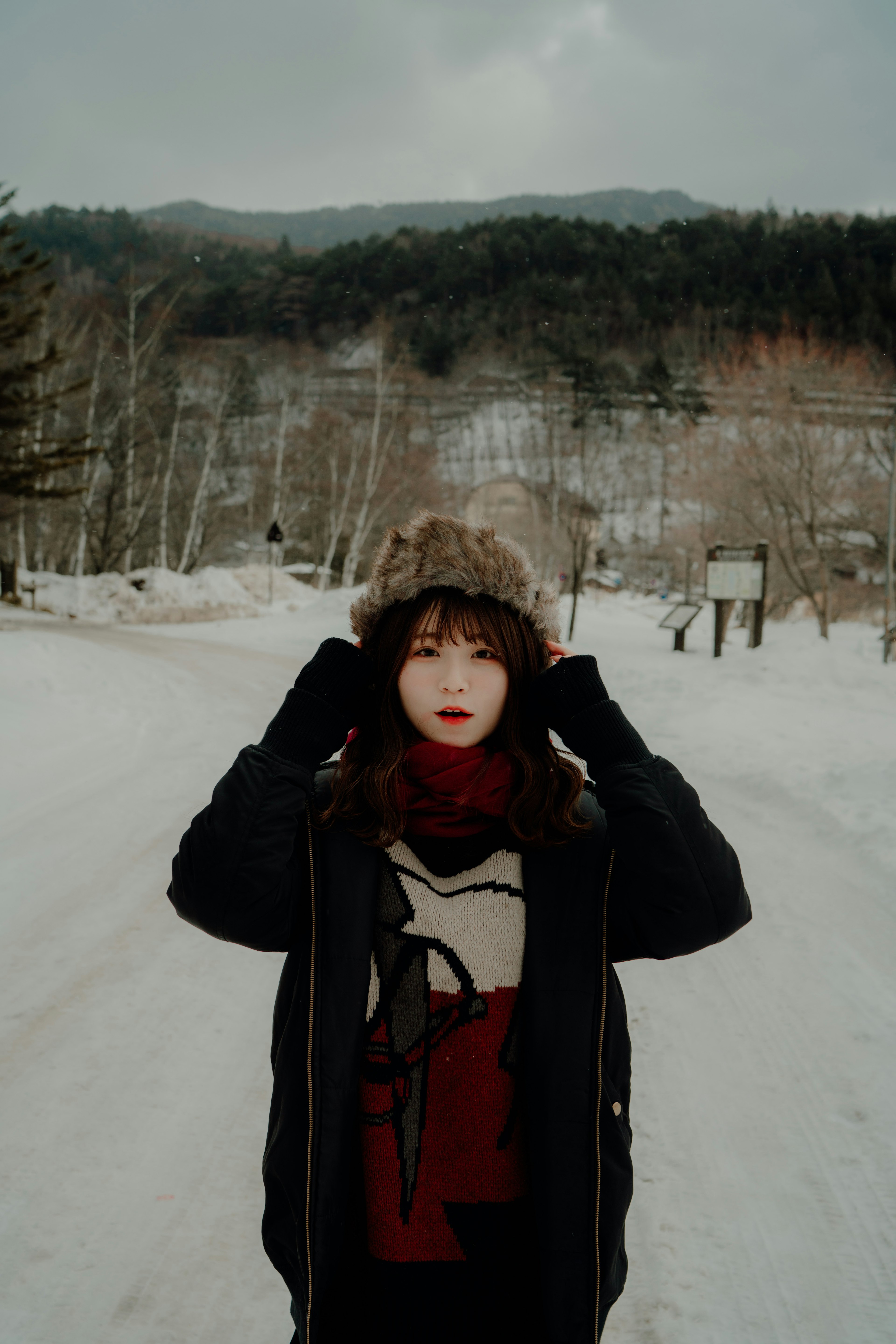 雪の中で帽子をかぶった女性が立っている風景