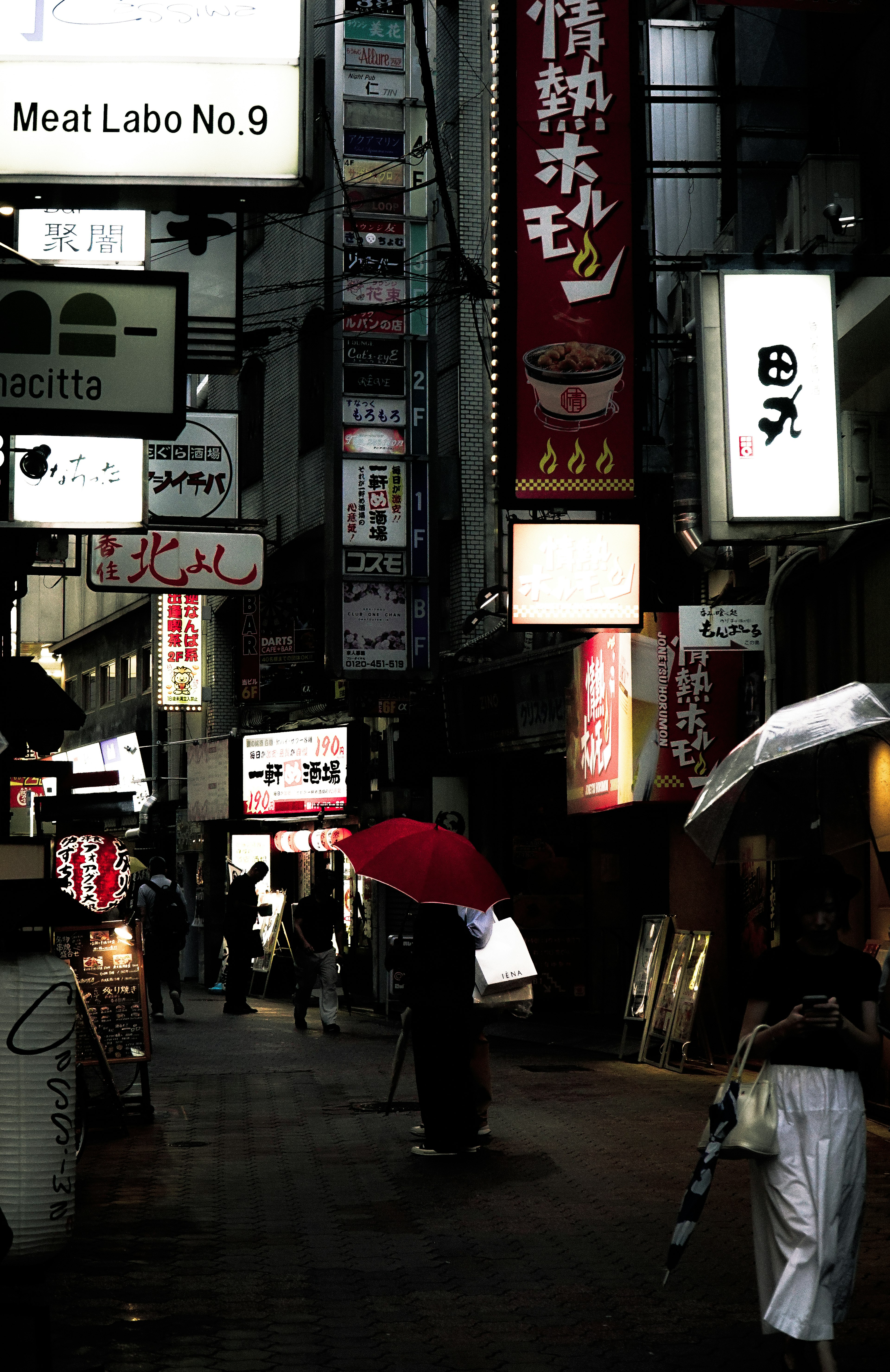 Dimly lit street scene with people holding umbrellas