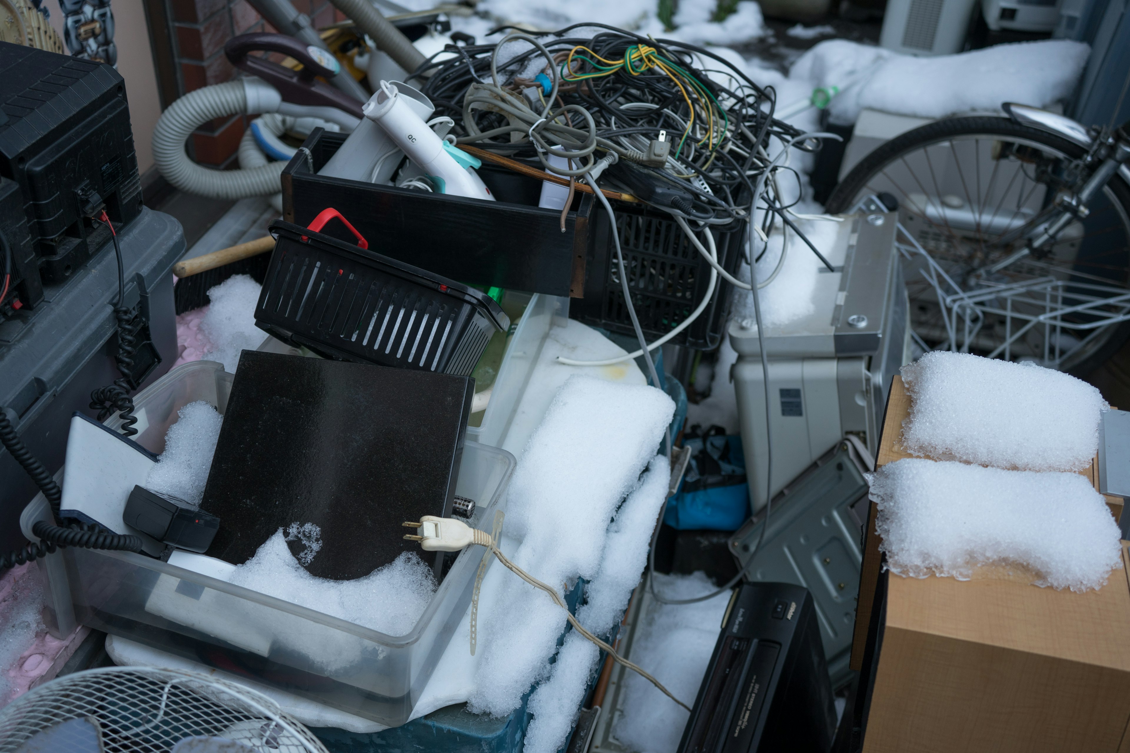 A clutter of old electronics and cables covered in snow