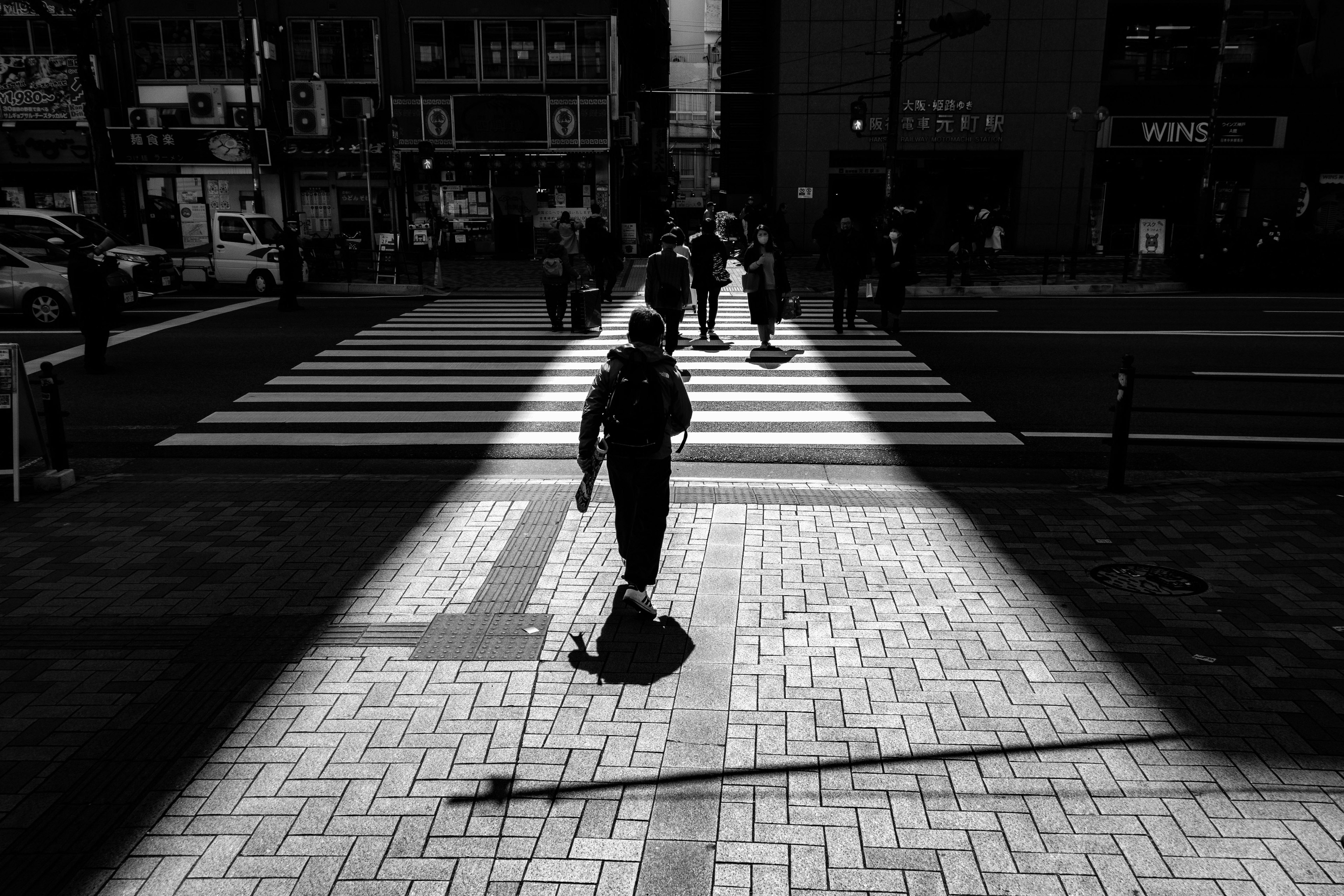 Silhouette of people walking in black and white at a crosswalk