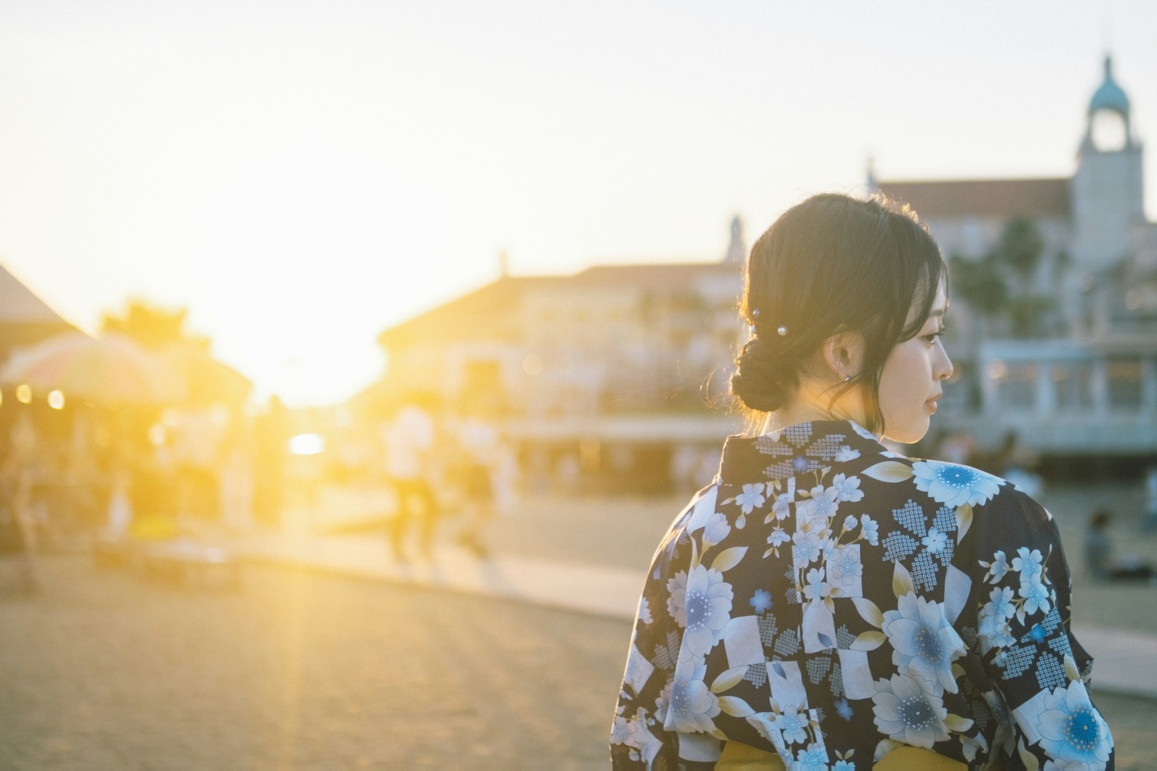 Una mujer en kimono de pie con el atardecer detrás de ella