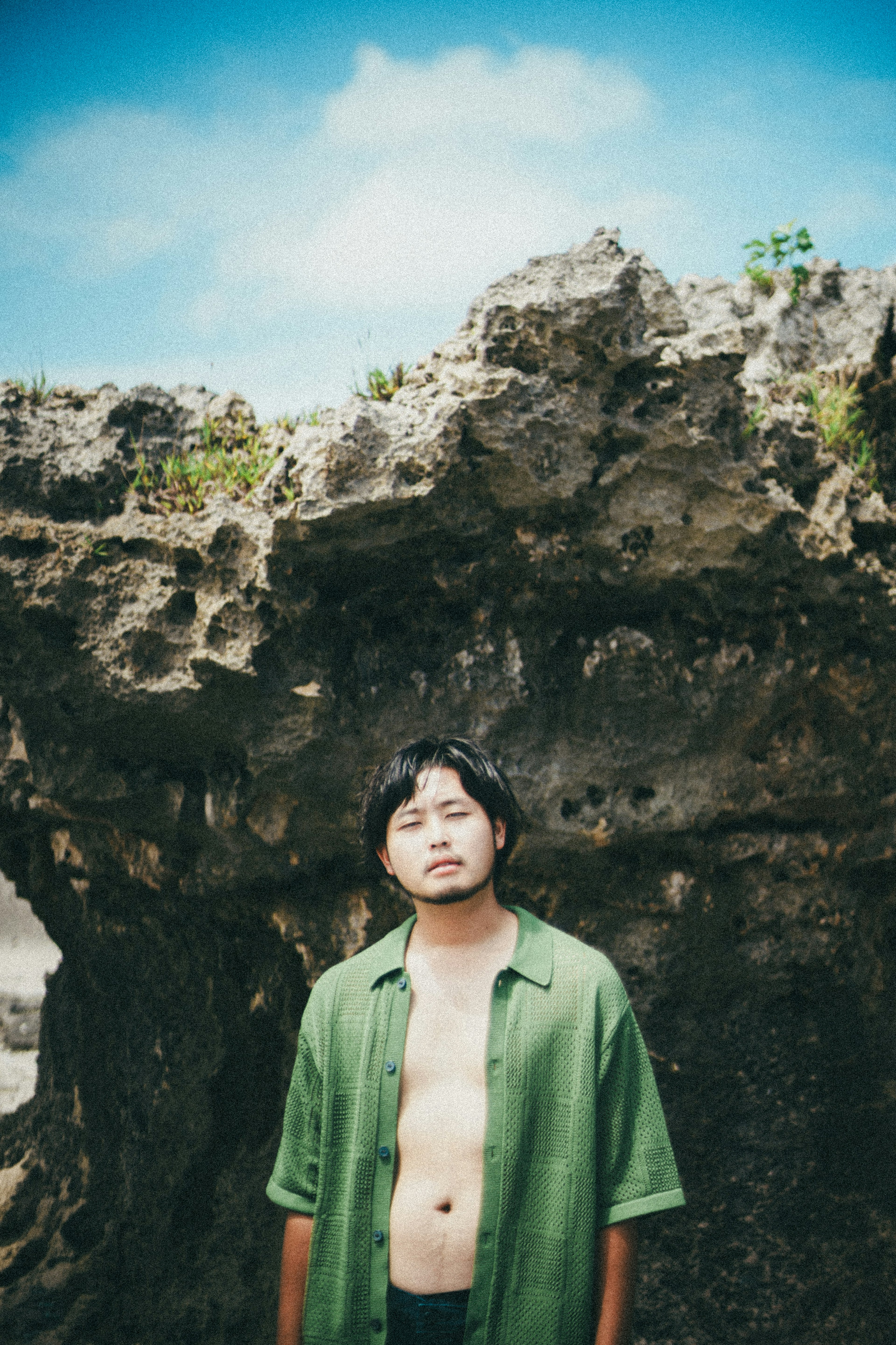 Portrait of a man standing in front of a rock under a blue sky