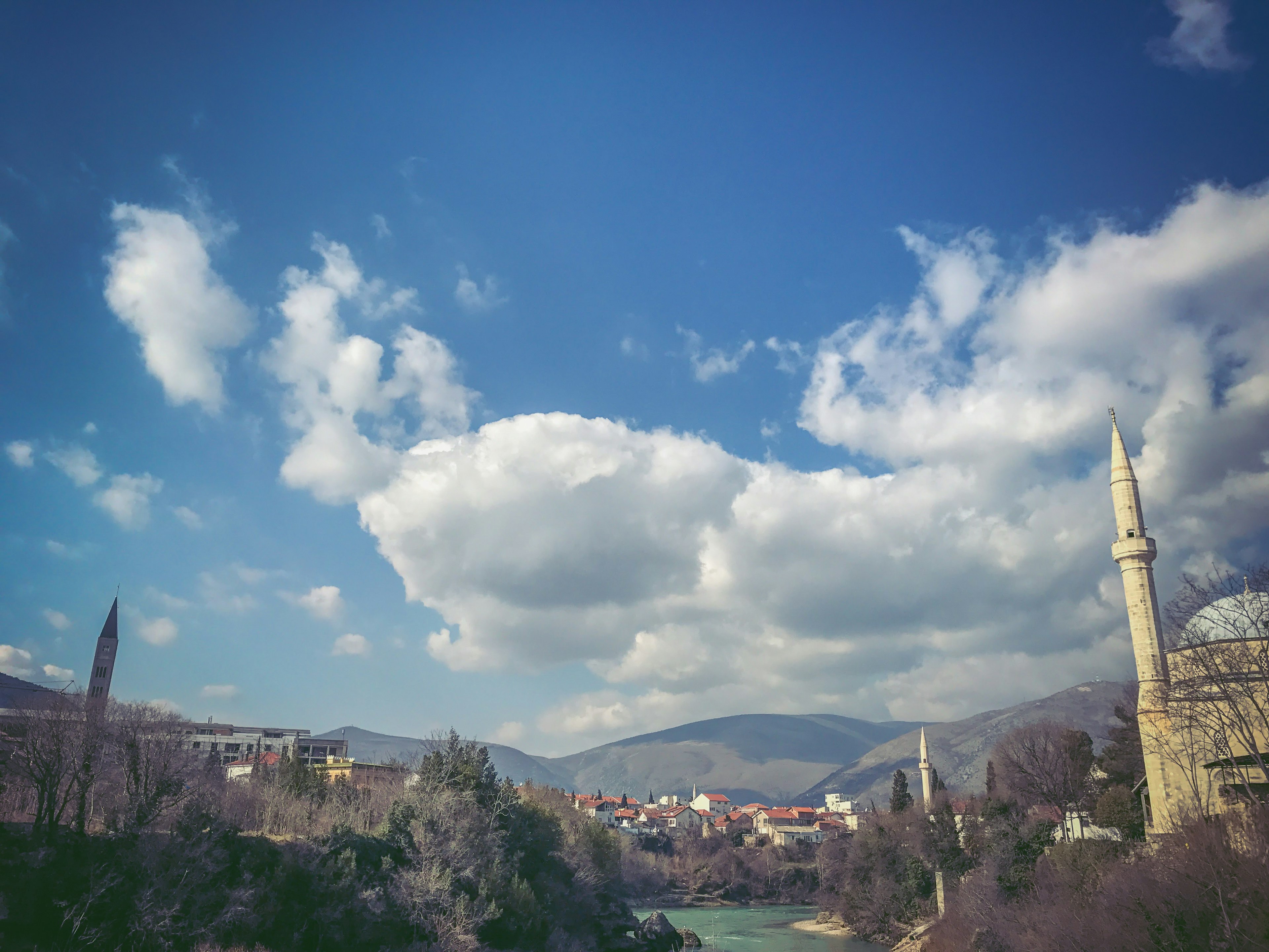 Scenic view featuring a mosque, mountains, and a river under a blue sky