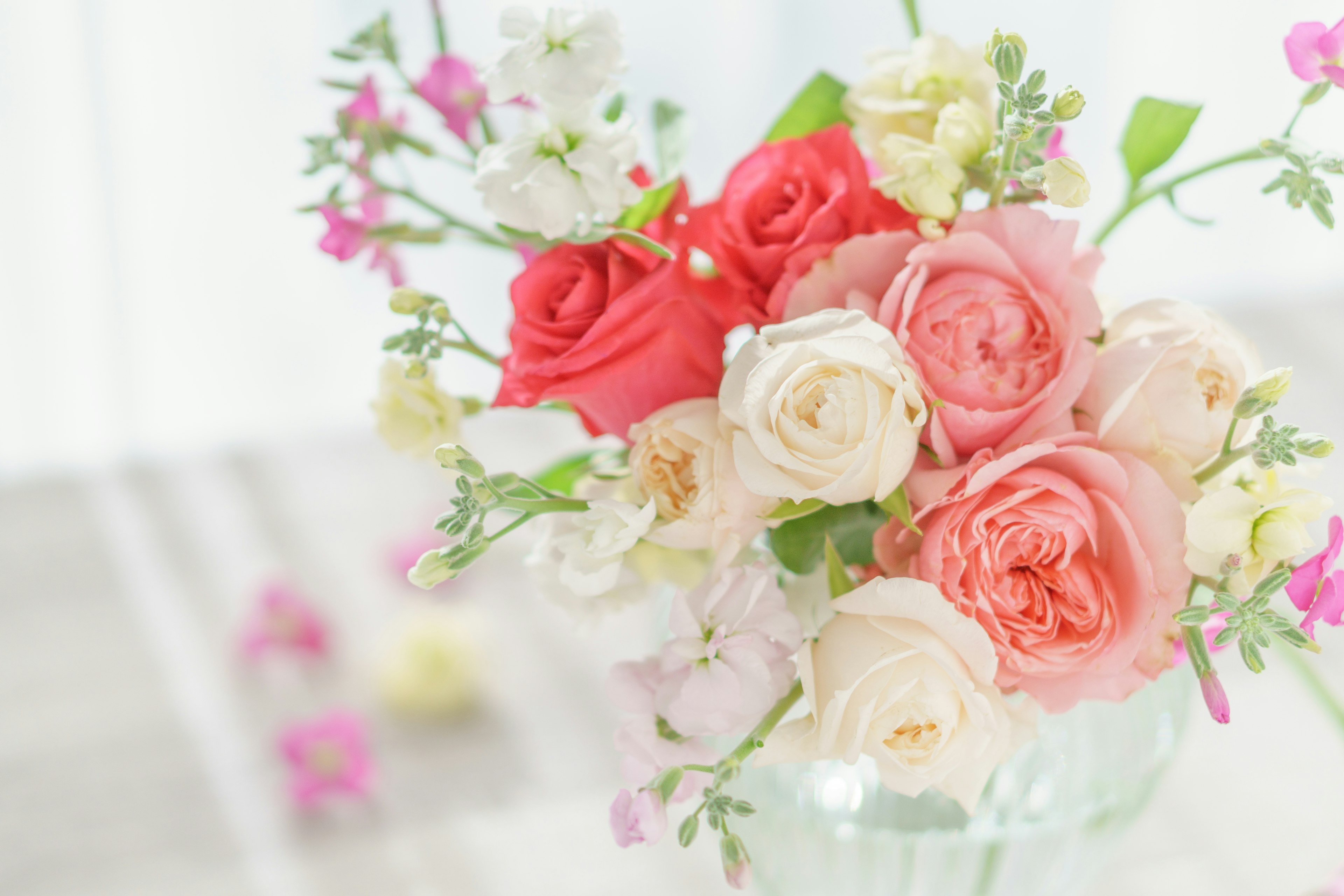 Un bouquet coloré de roses et de petites fleurs disposées dans un vase en verre