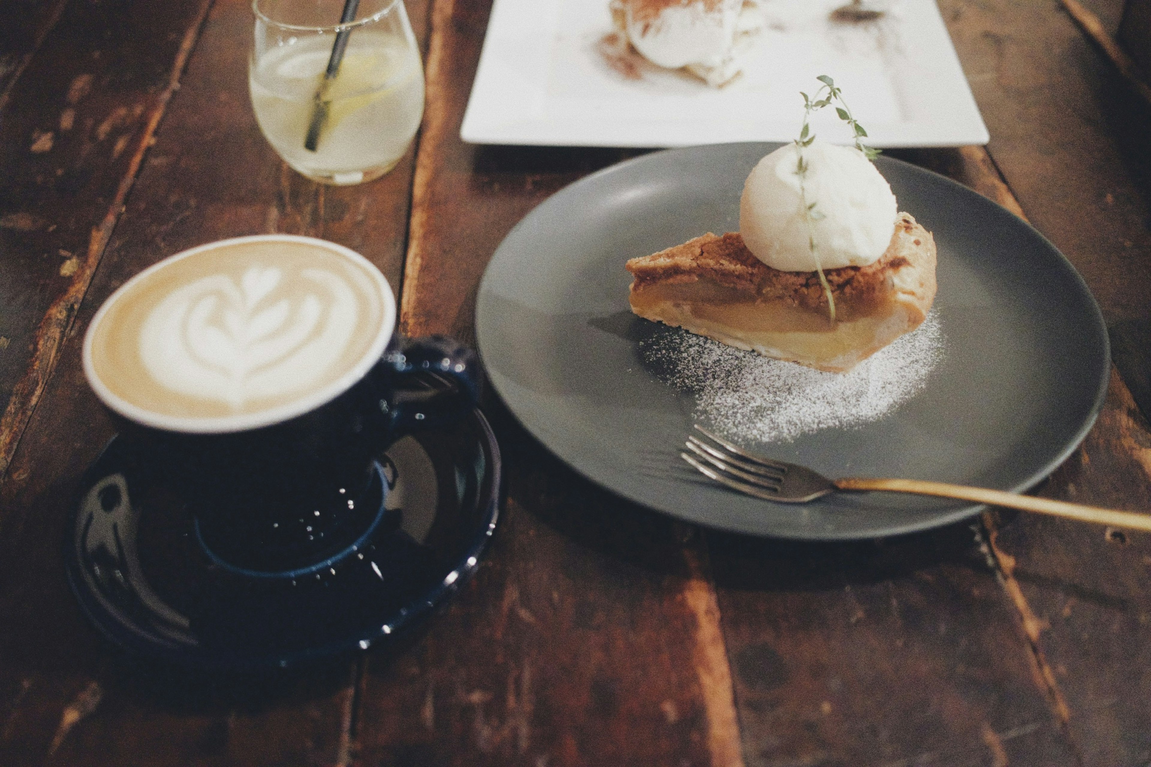 Arreglo de café y postre con un pastel con cobertura de crema y helado