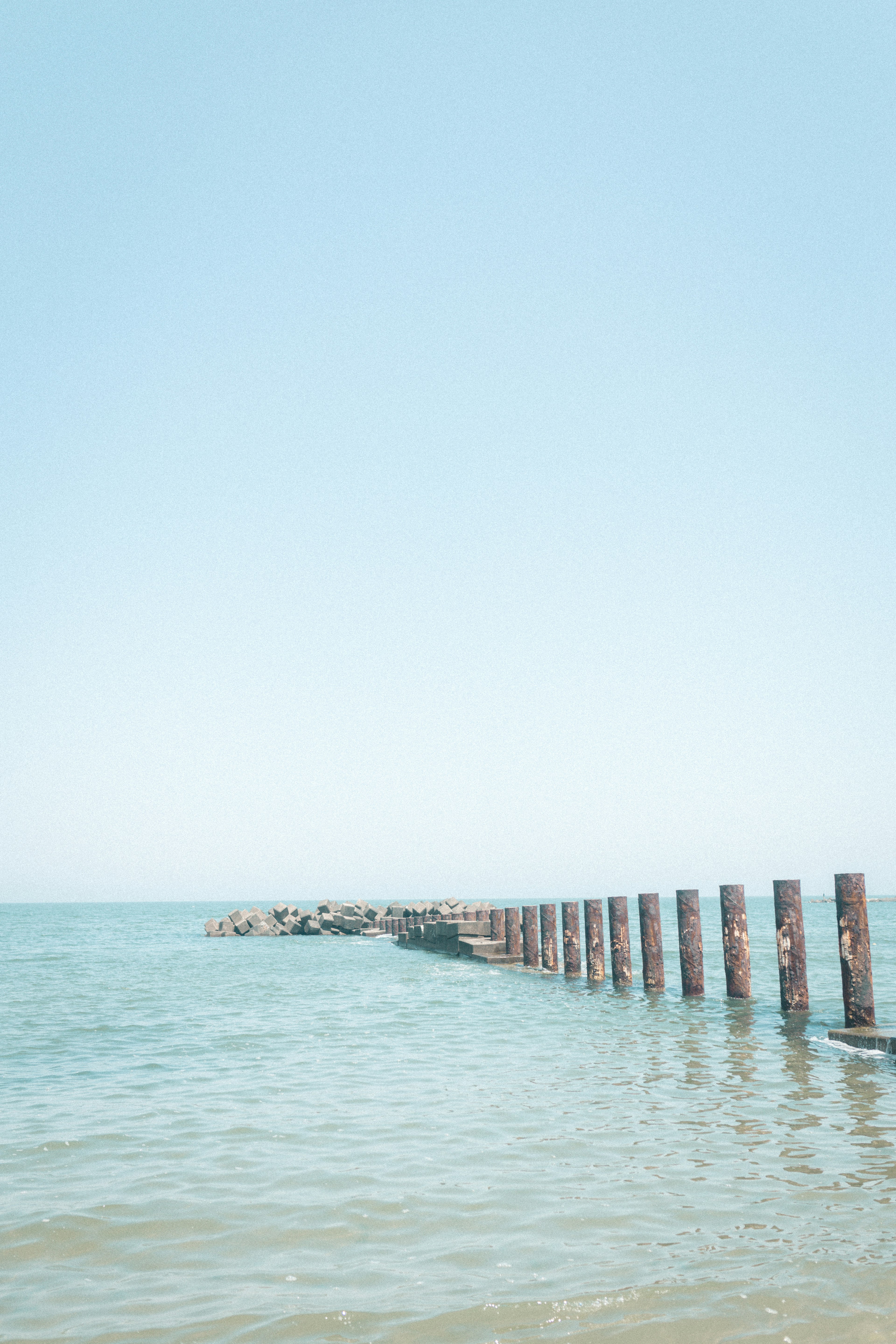 Pier extending into calm water under clear blue sky