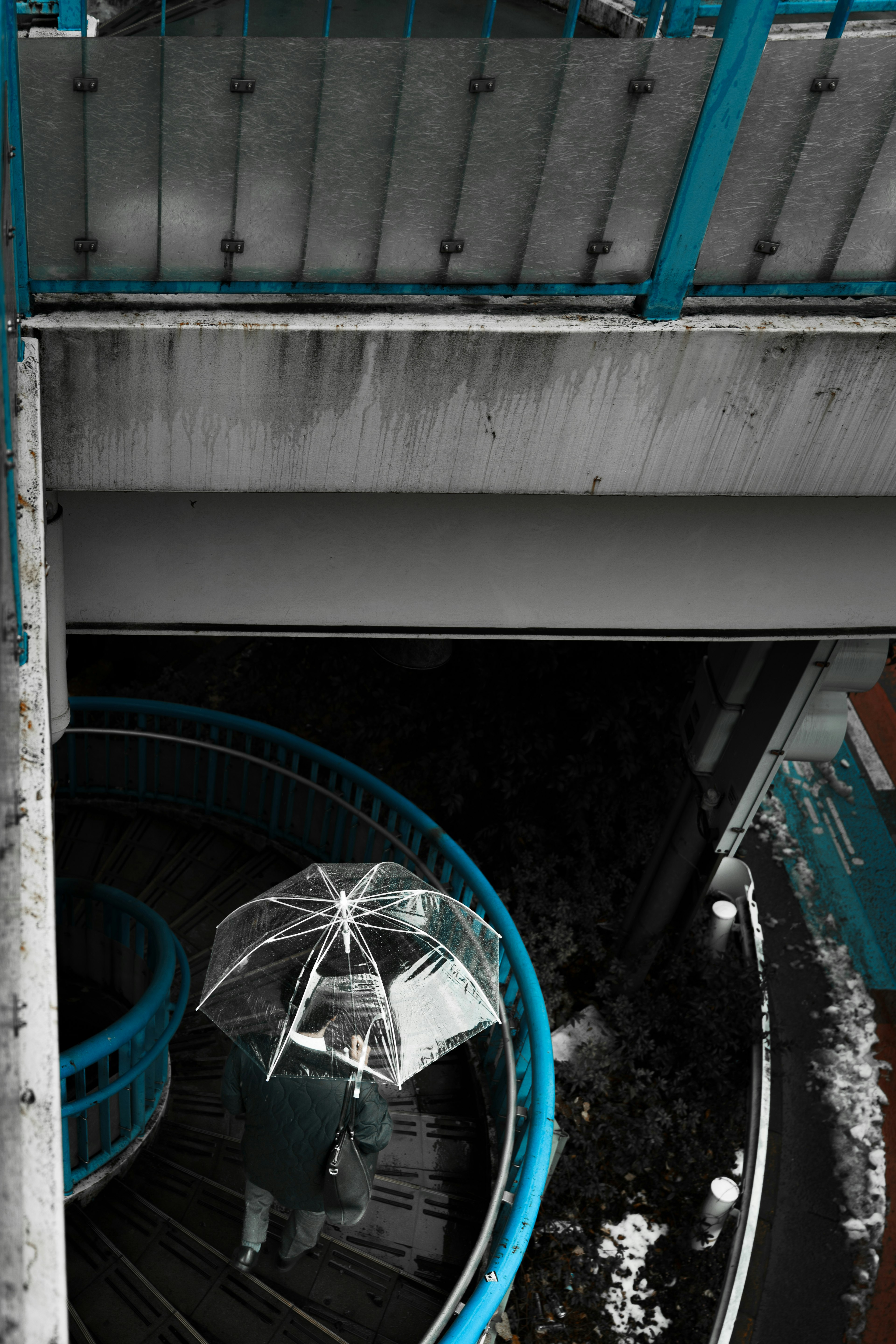 Eine Person, die eine Wendeltreppe mit einem weißen Regenschirm hinuntergeht