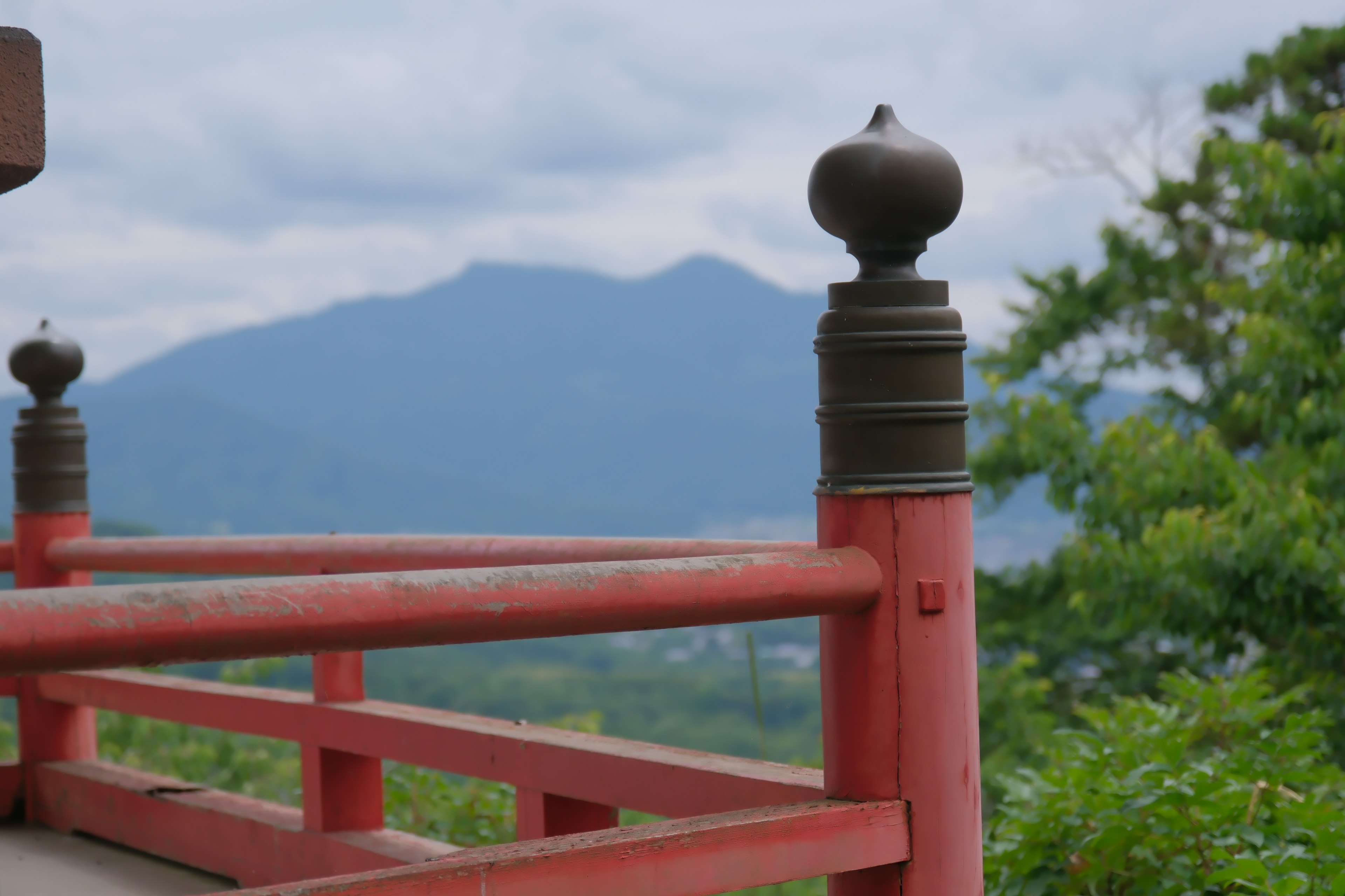 Railing rosso con ornamento metallico e montagne sullo sfondo