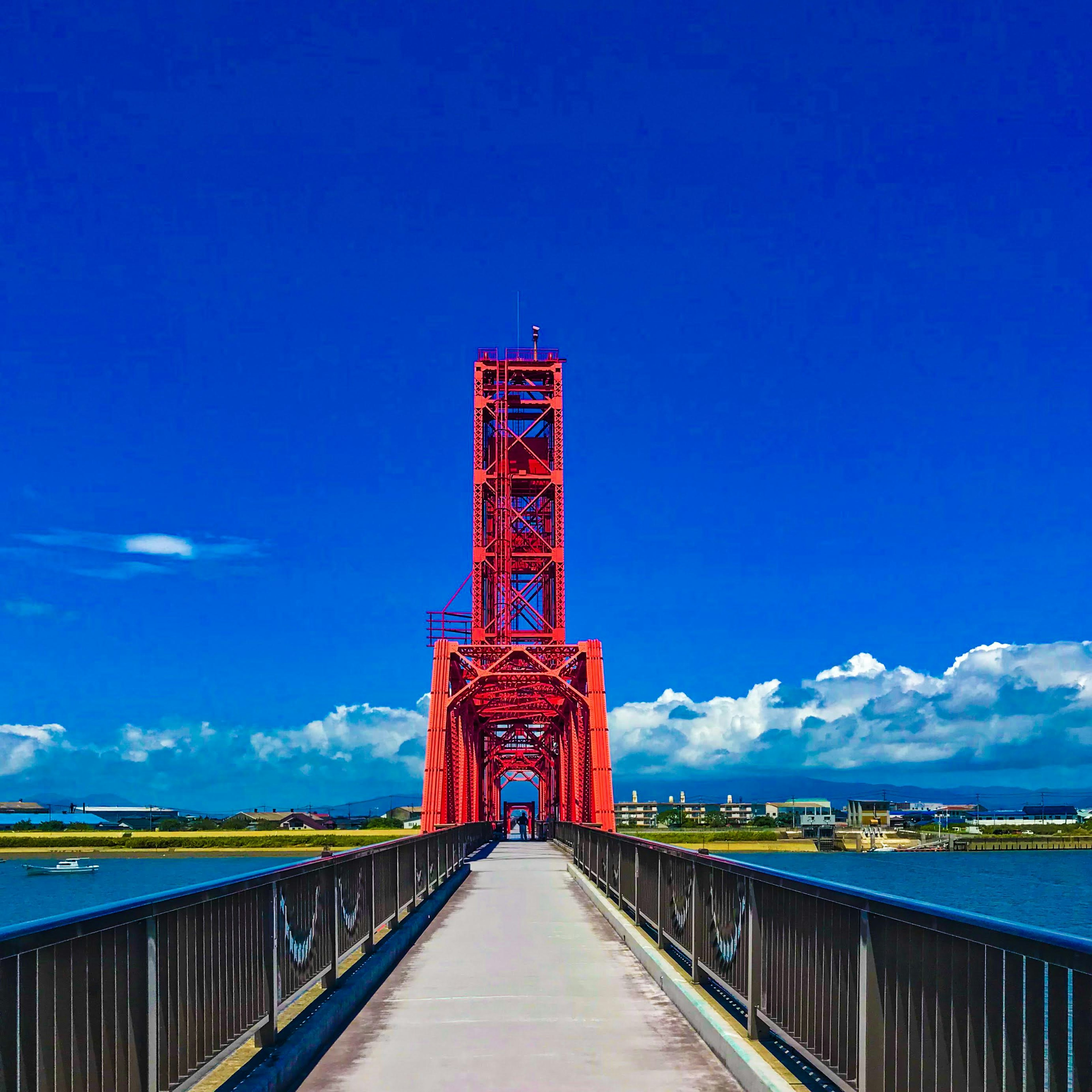 Red bridge tower against a blue sky and sea