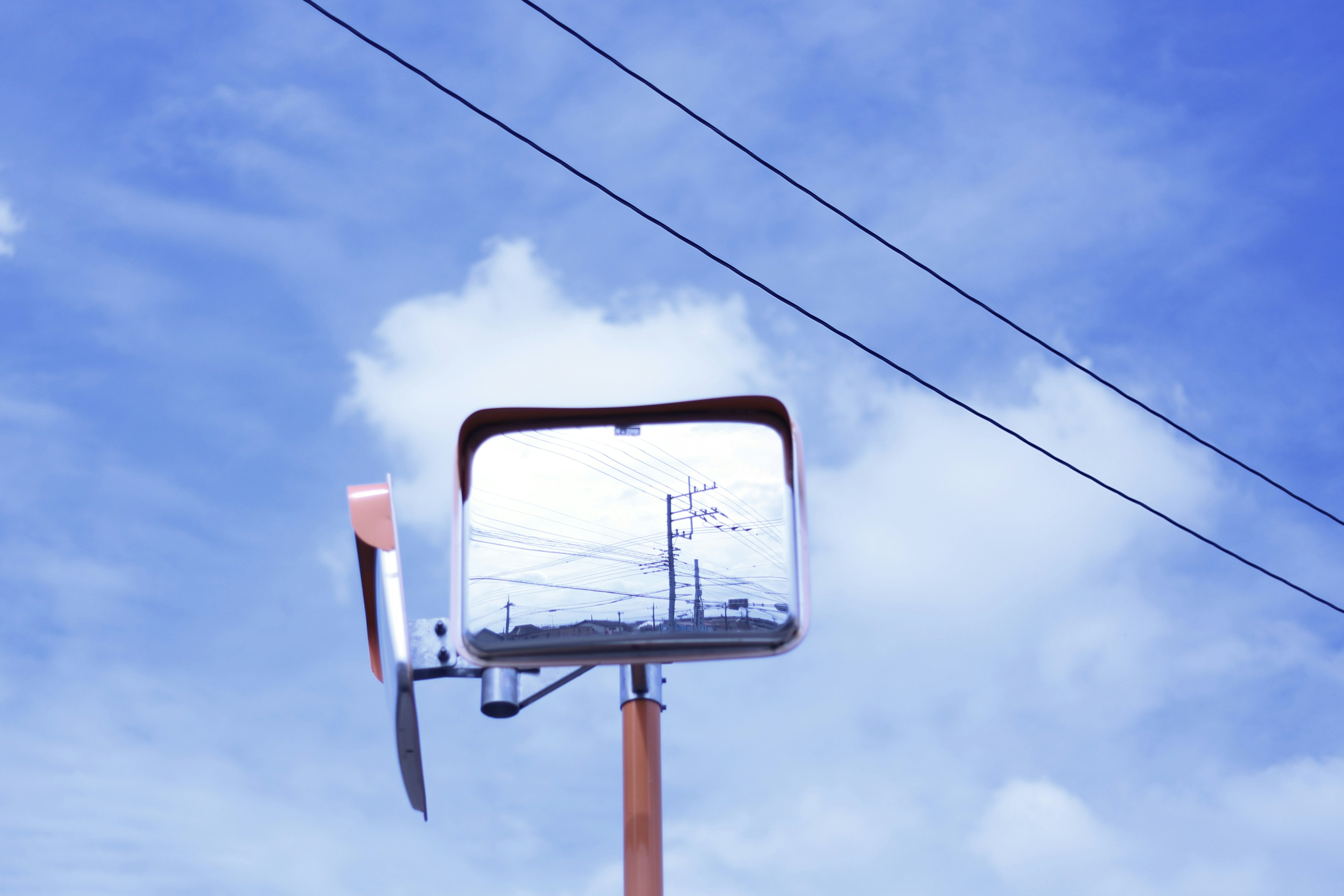 Grande specchio riflettente sotto un cielo blu con linee elettriche