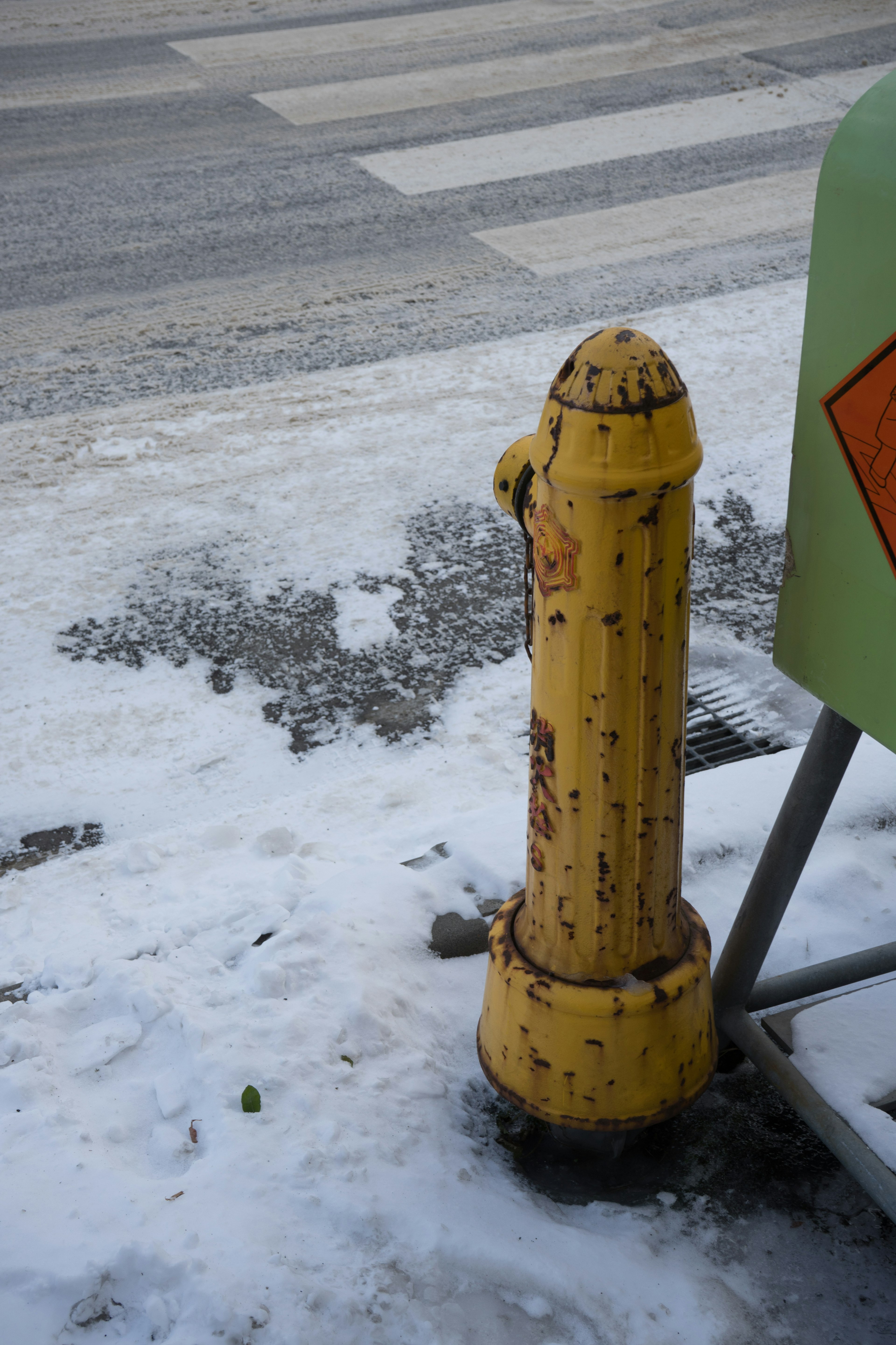 雪の上に立つ古い黄色い消火栓が目立つ