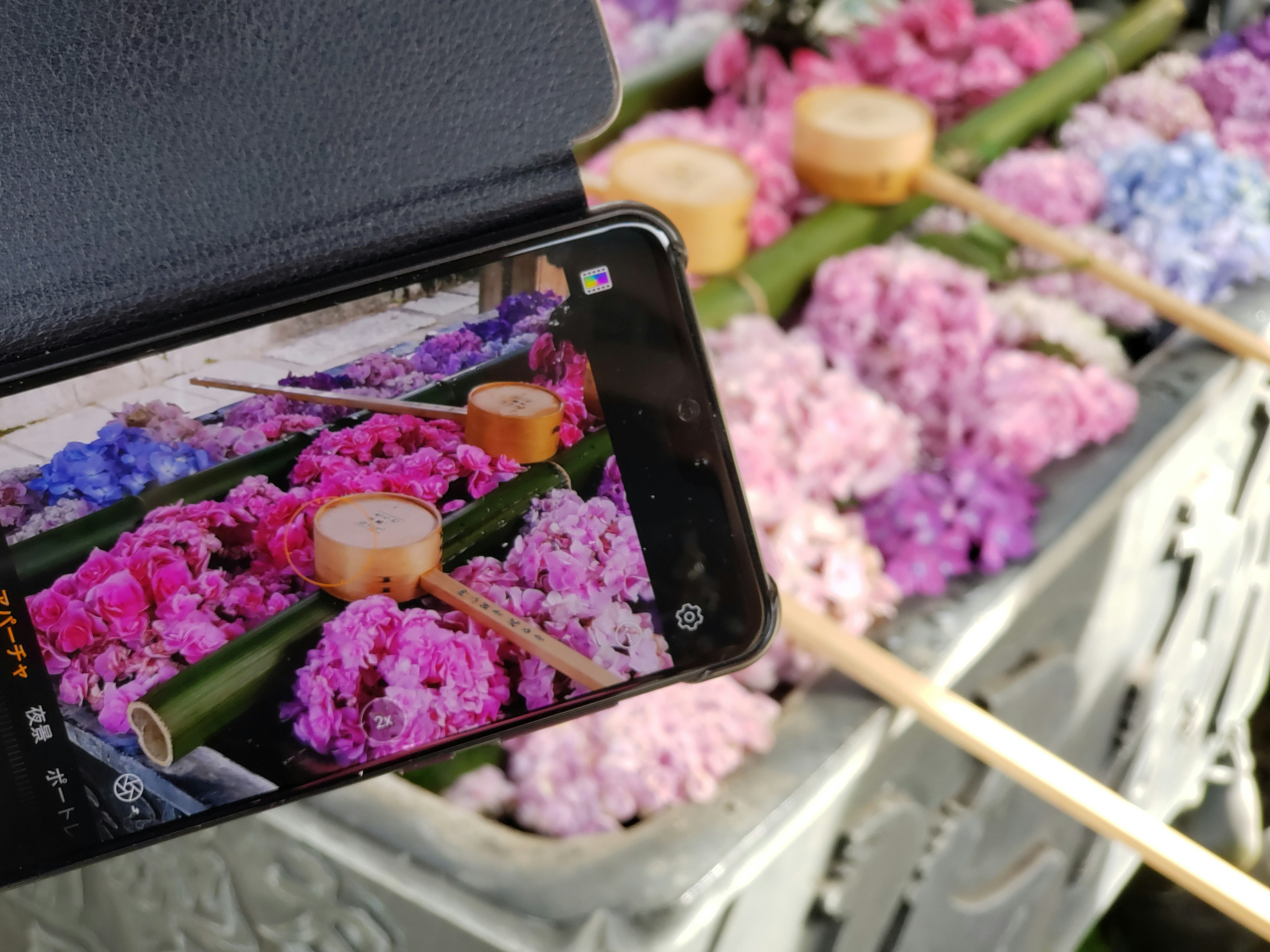 Uno smartphone che cattura un'esposizione colorata di fiori in un cesto con elementi in bambù