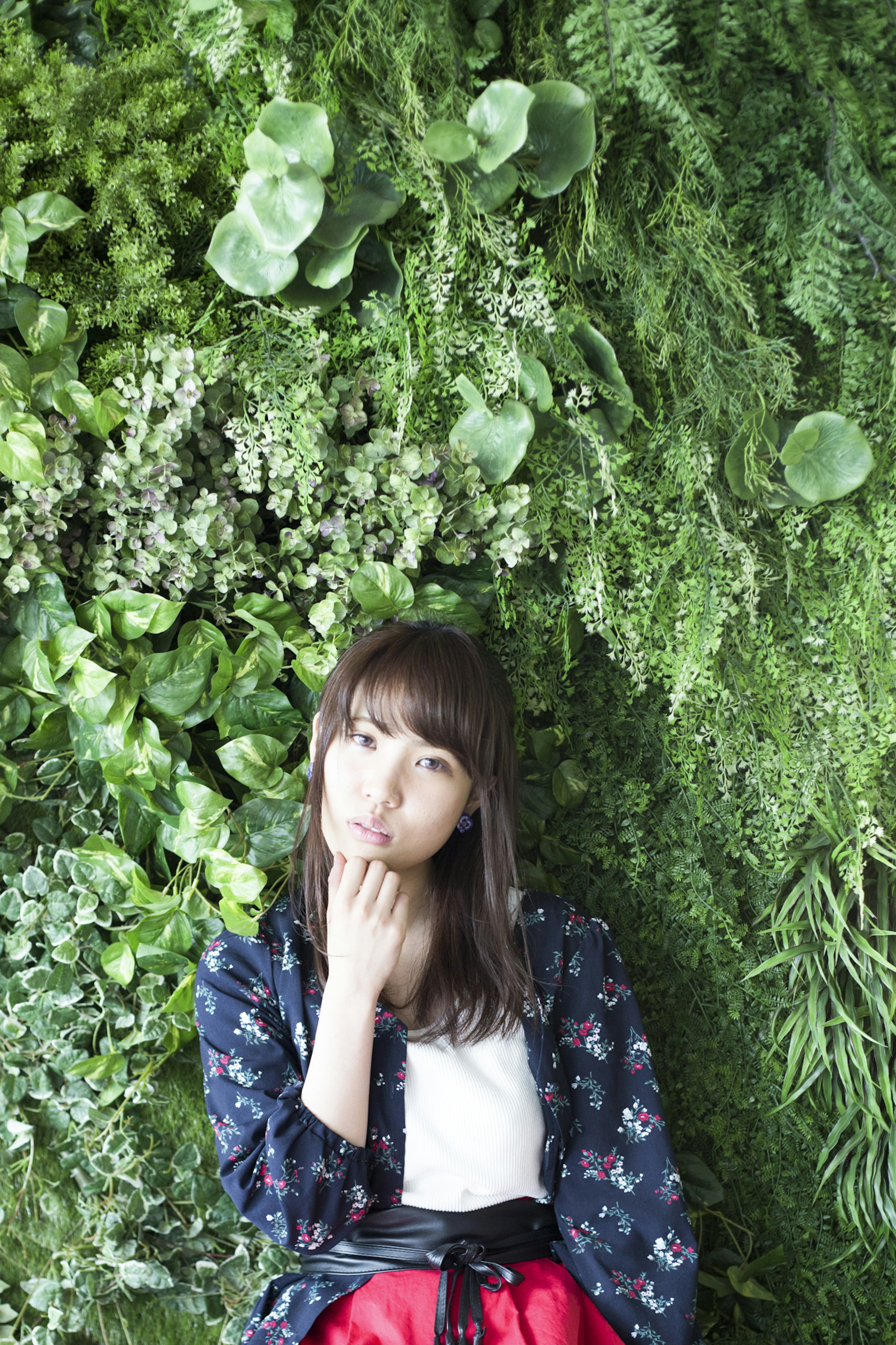 Portrait of a woman in front of a green wall displaying a thoughtful expression