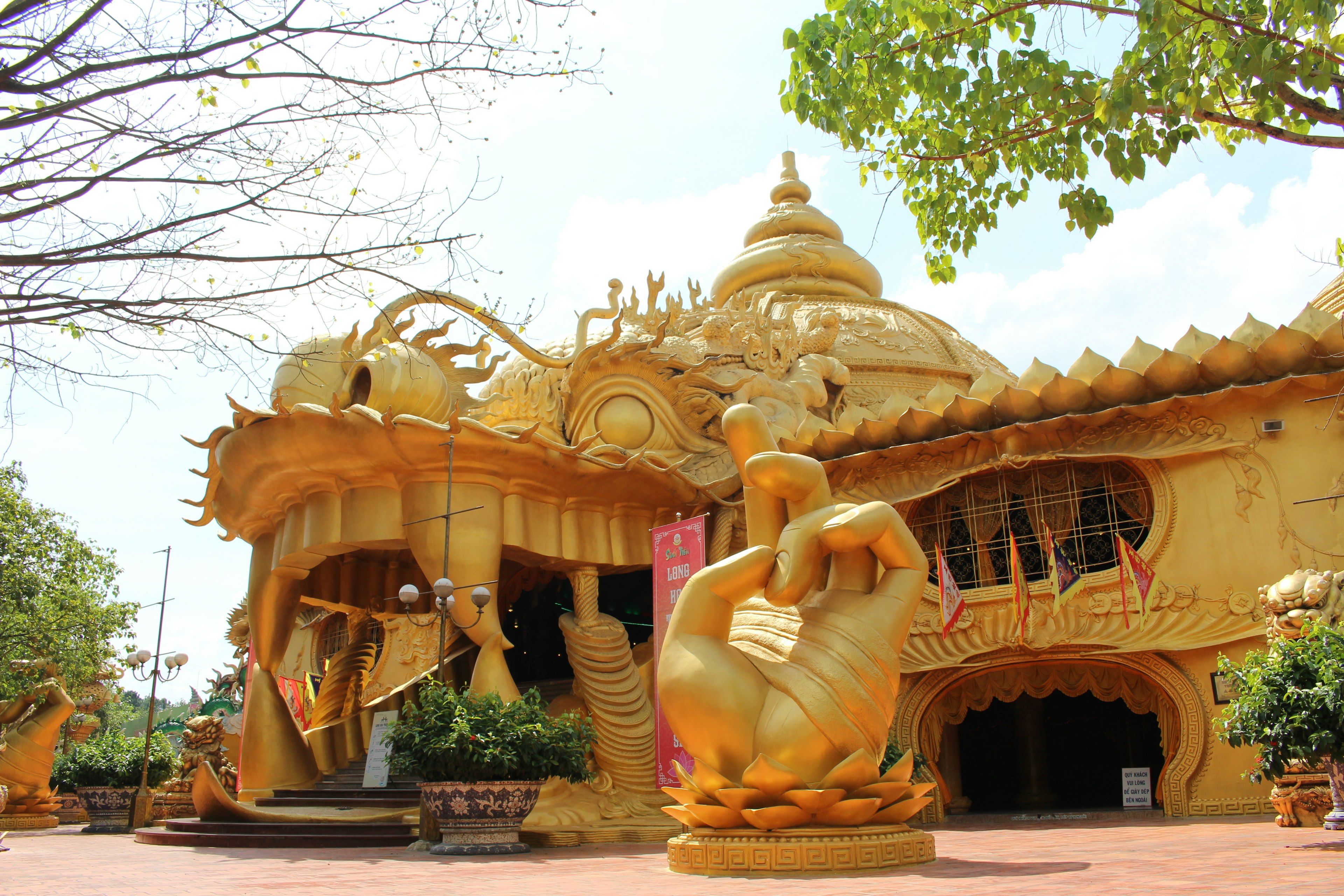 Extérieur d'un temple doré avec une grande sculpture de main et des détails complexes