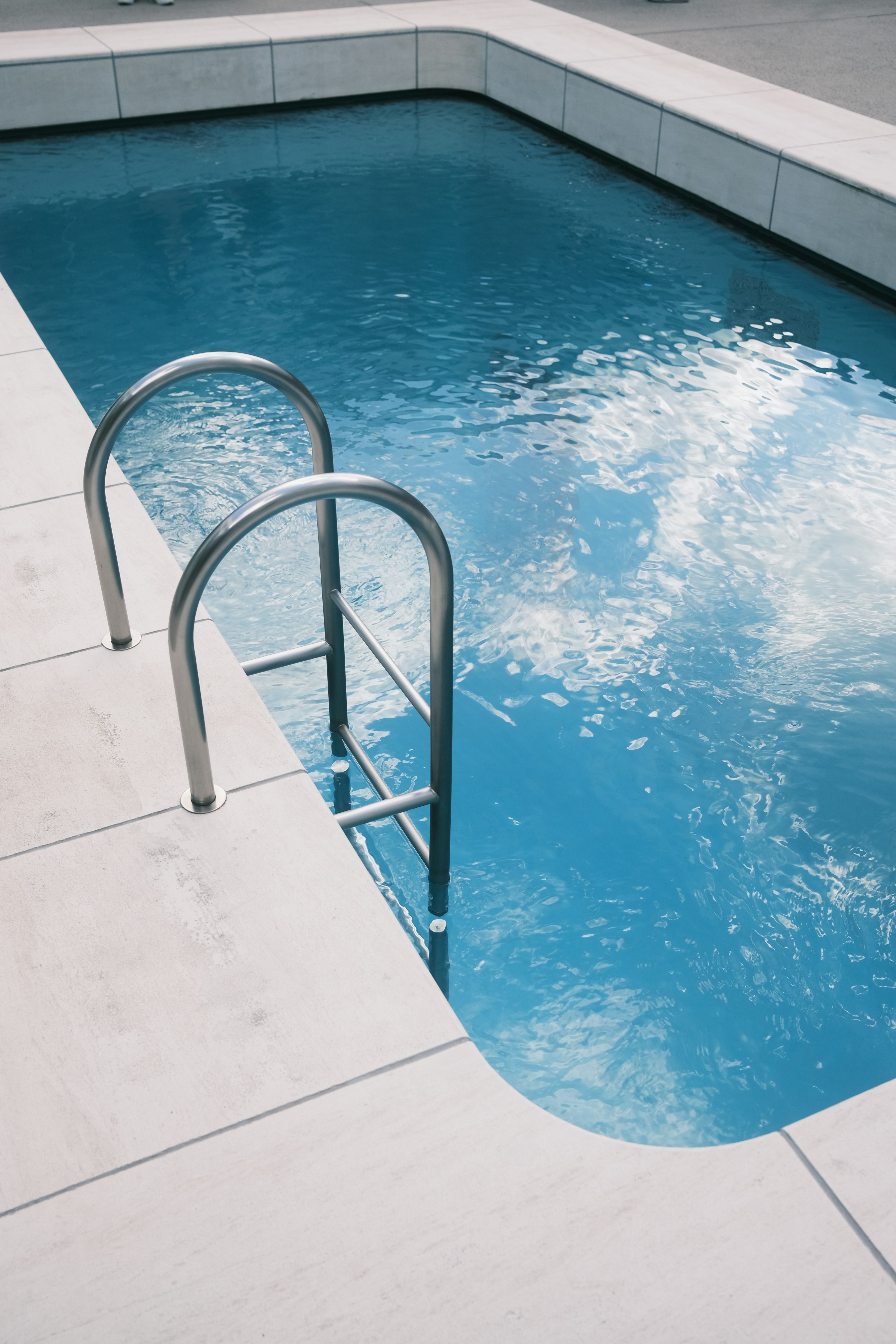 Piscina con agua azul y escalera de metal