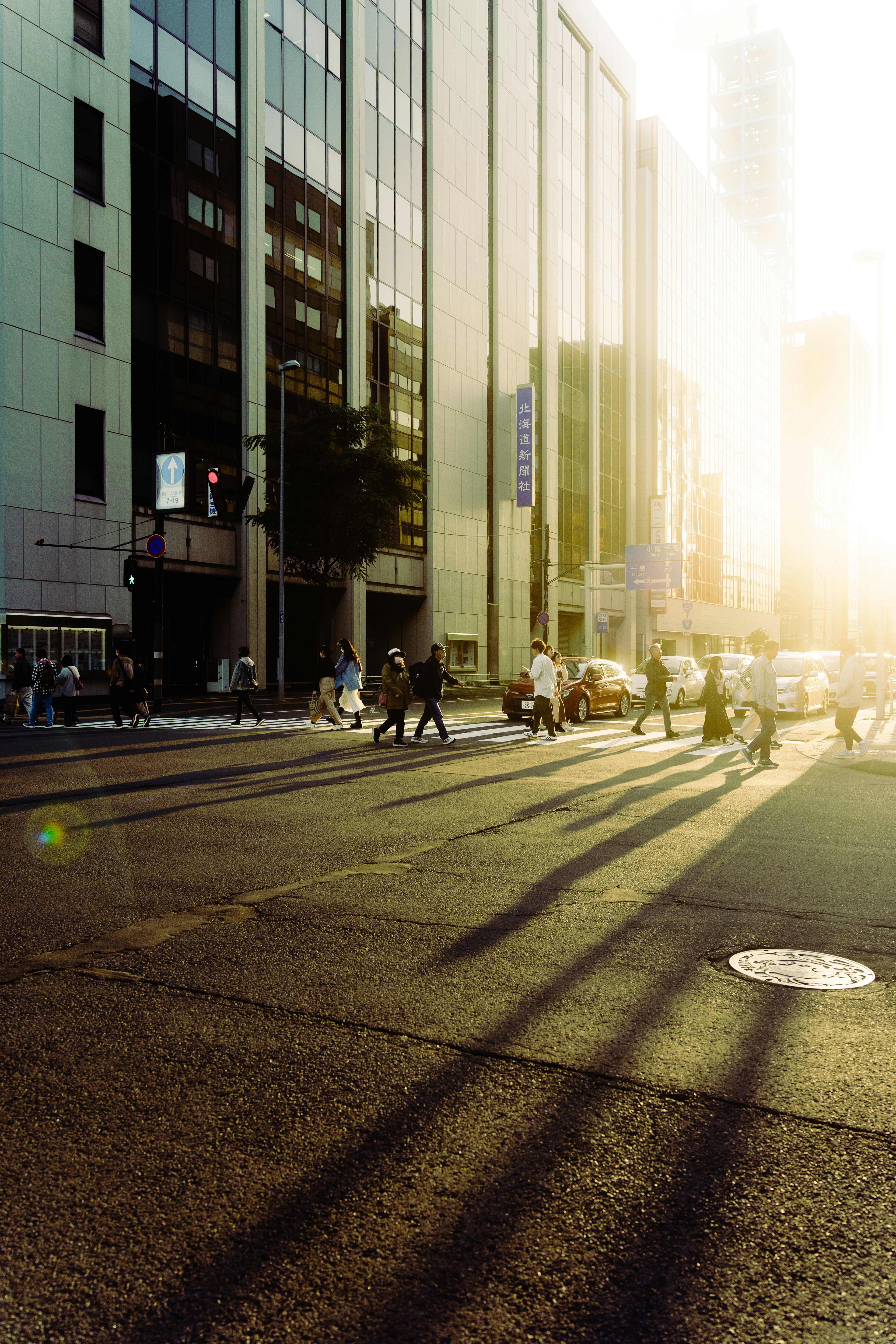 Persone che attraversano un incrocio urbano illuminato dalla luce del tramonto