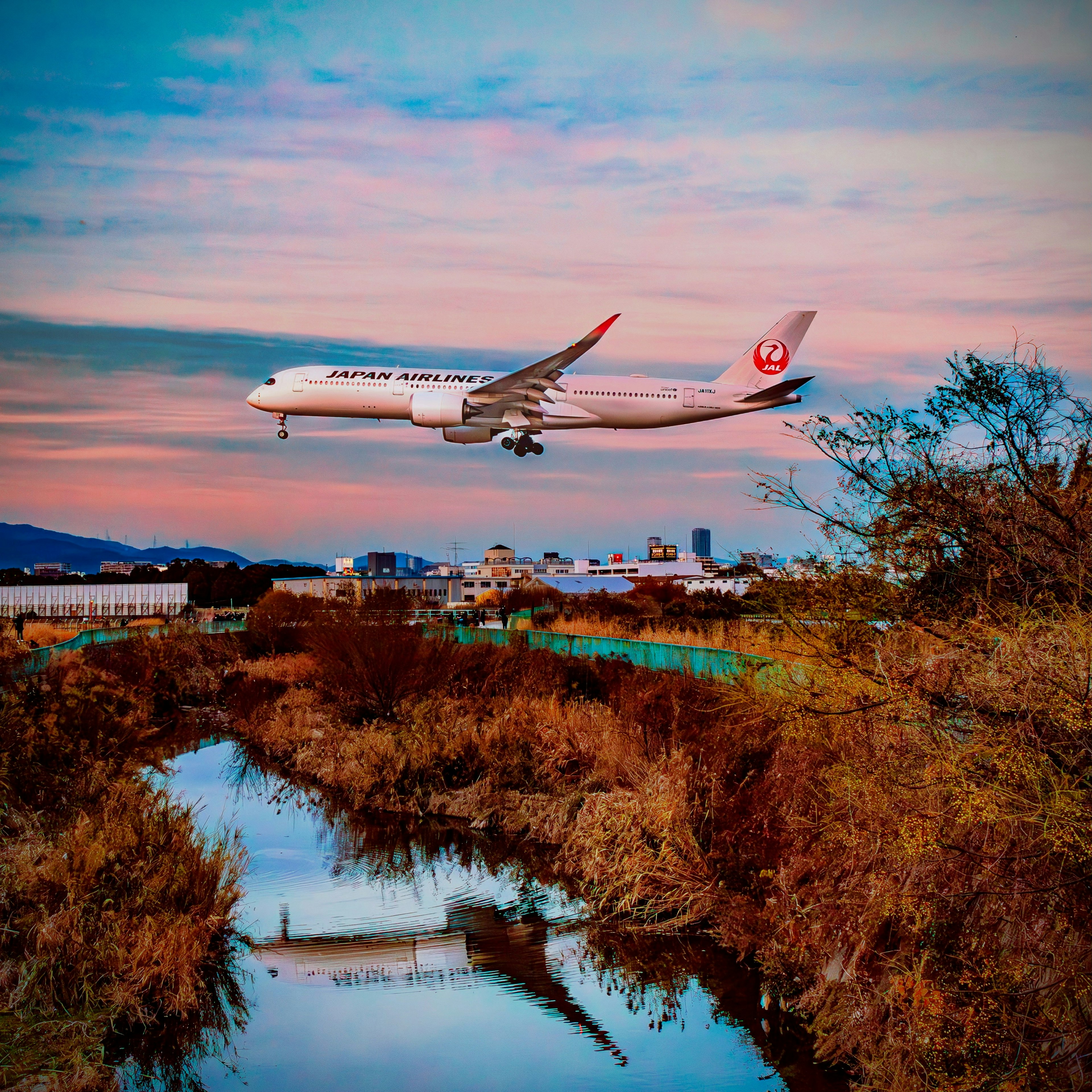 日本航空飛機在日落時飛越河流