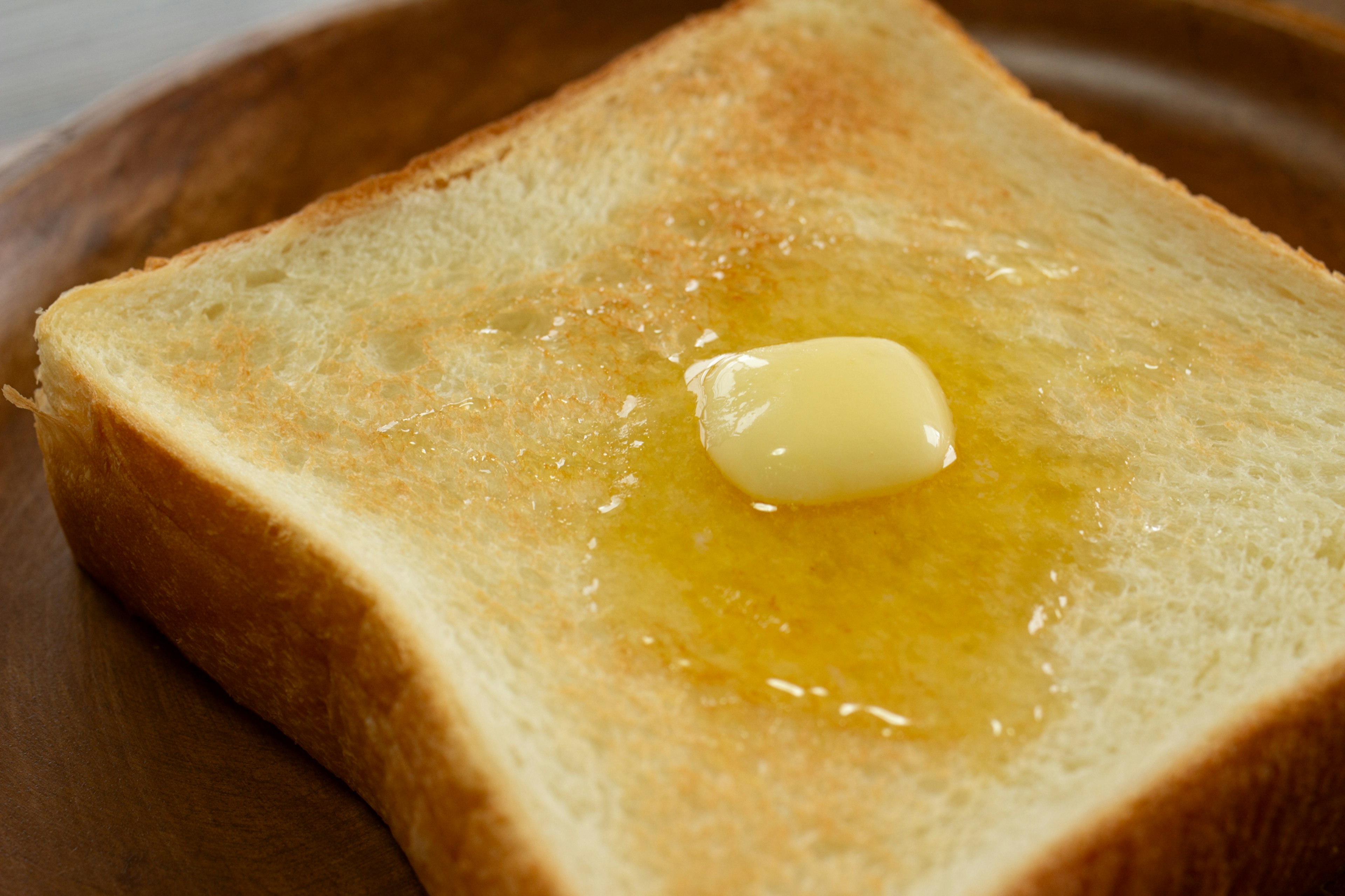 Roti bakar dengan mentega dan madu disajikan di piring kayu