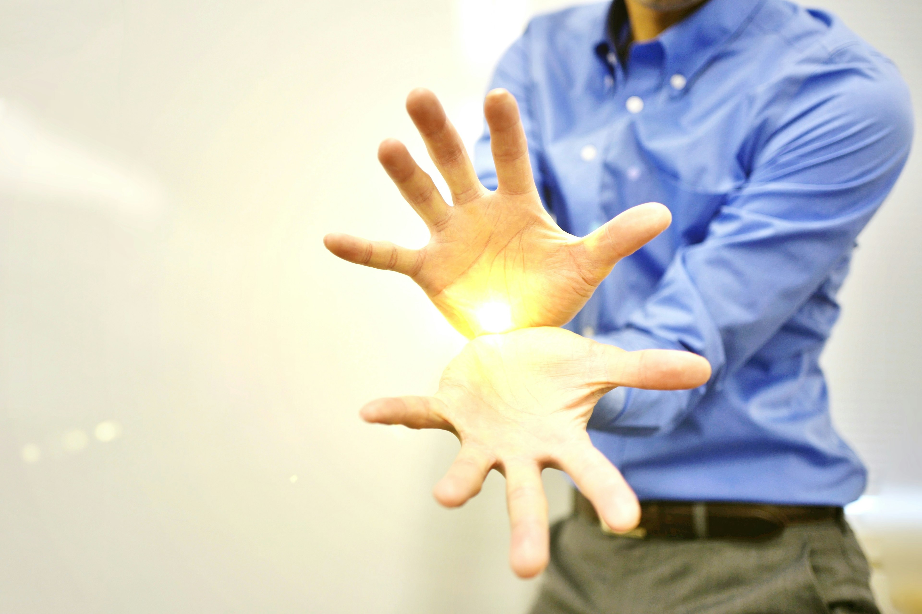 Man in a blue shirt extending hands with glowing light between them