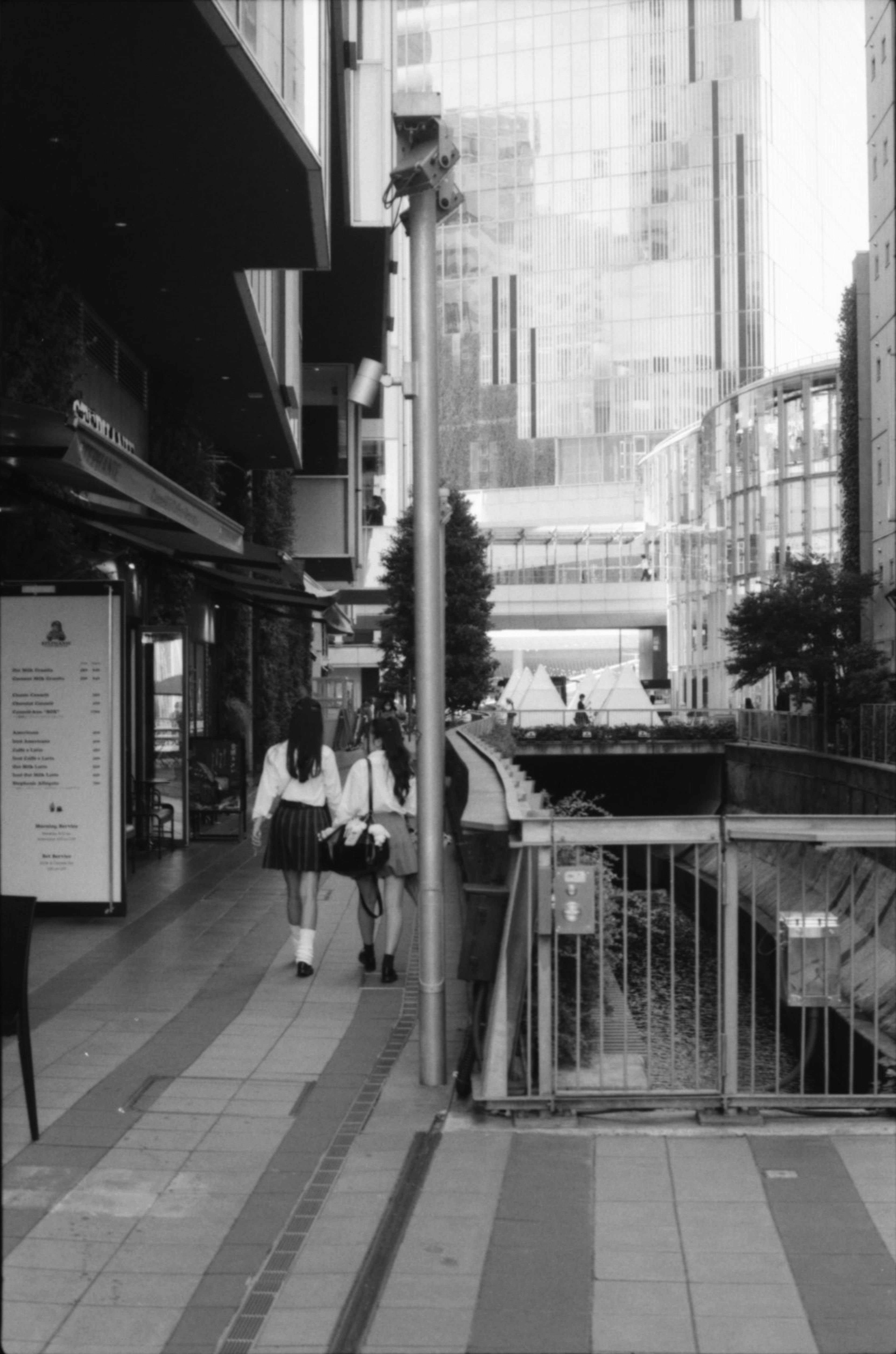 Two people walking in a monochrome urban setting with buildings in the background