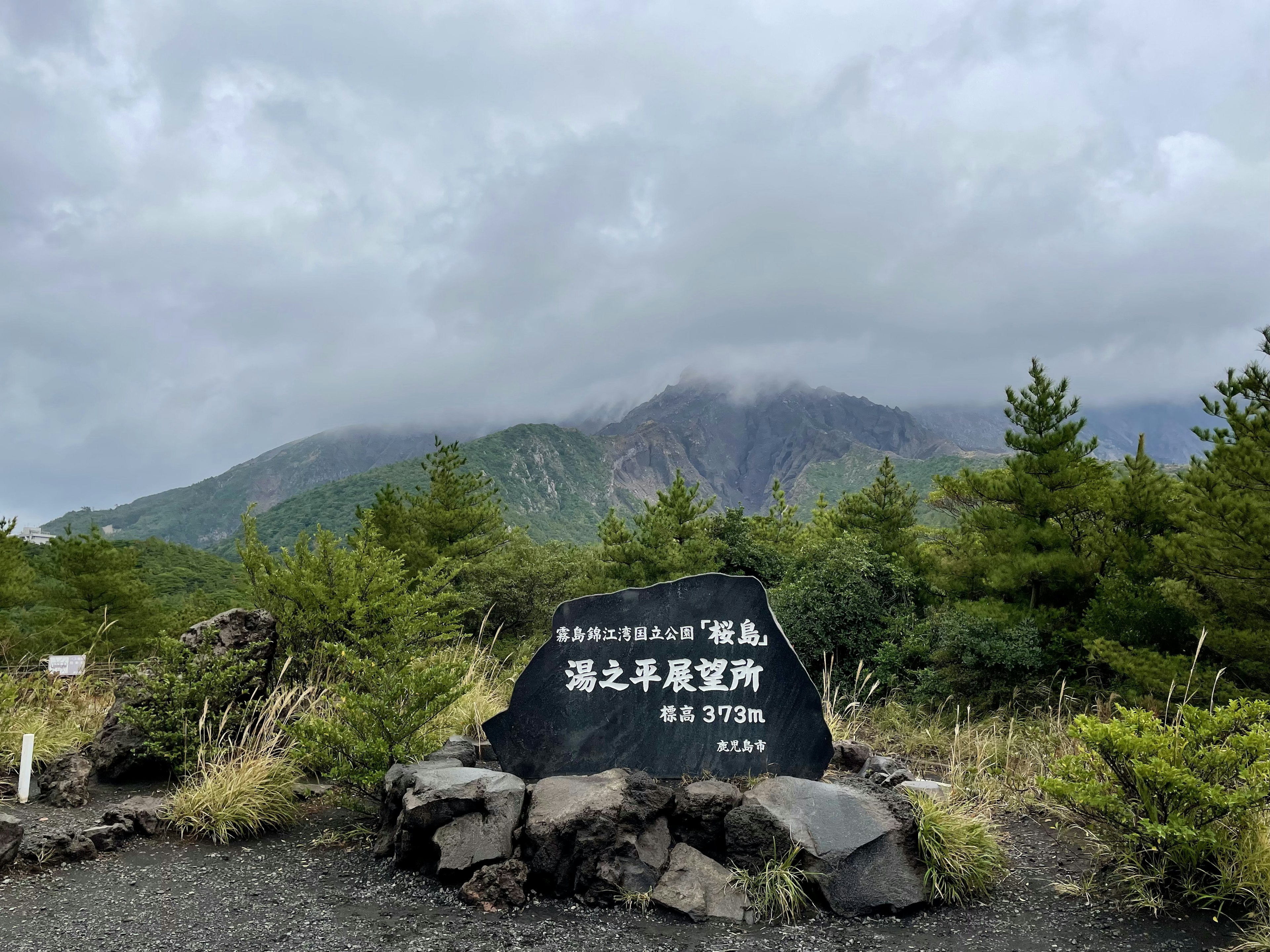 Panneau en pierre noire entouré de montagnes et de nuages