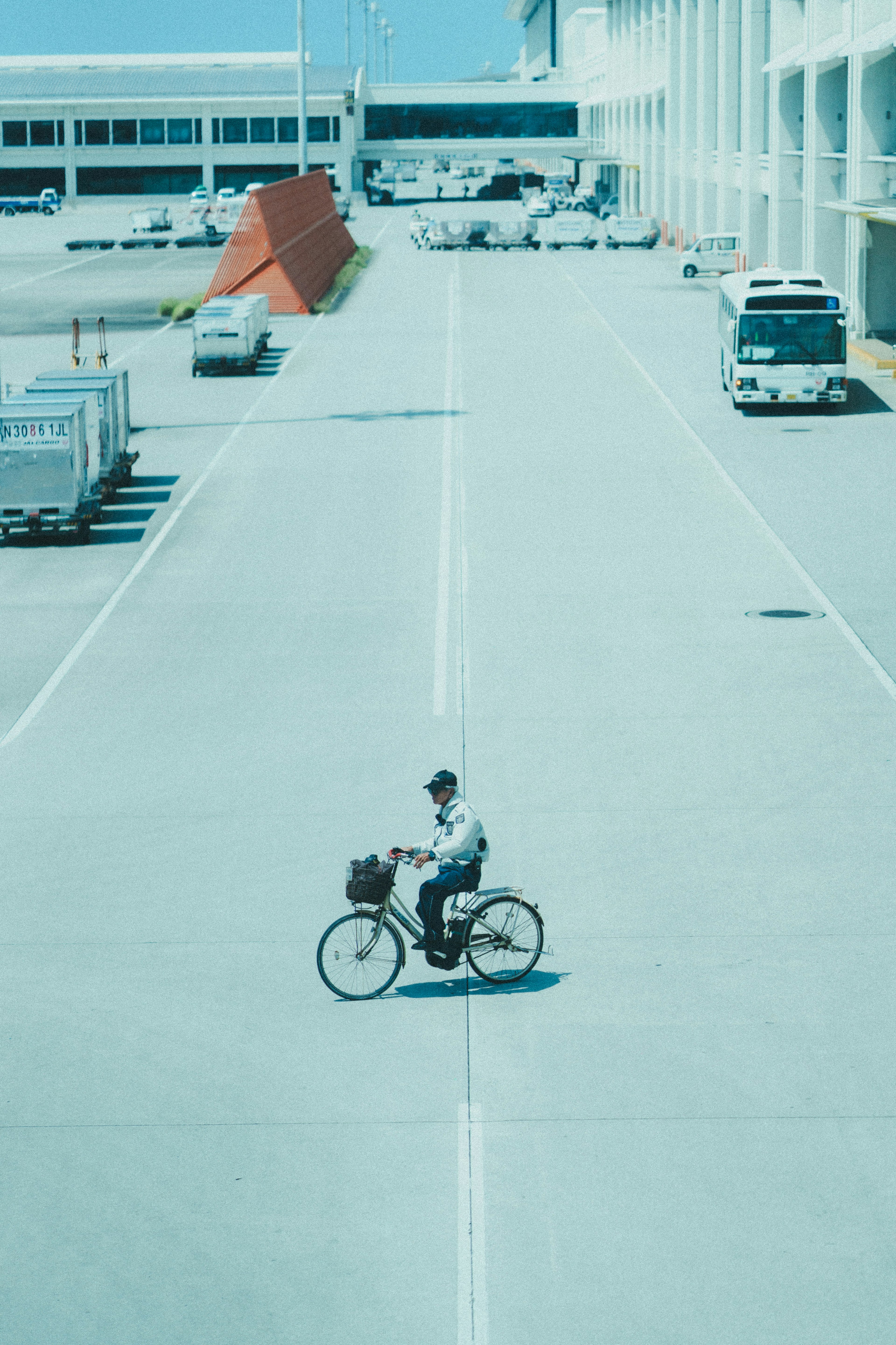 空港の通路を自転車で走る男性と周囲の車両